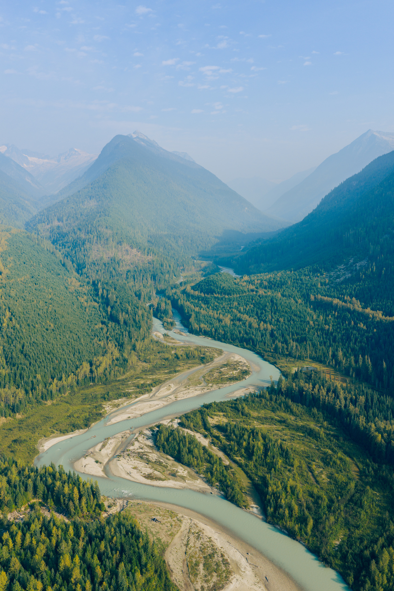 The river braiding down a long forested valley