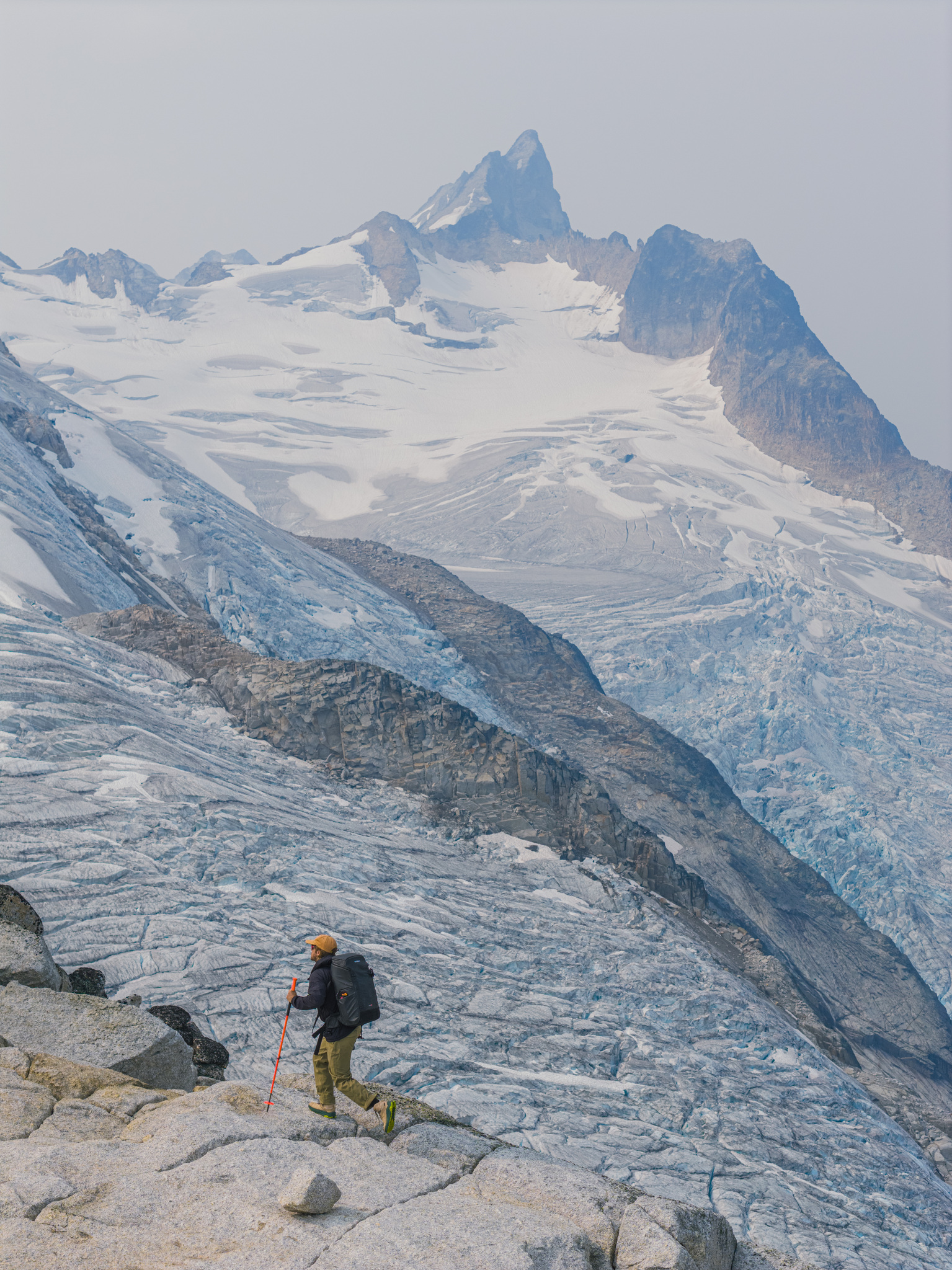 A hiker on the slabs above a broad glacier