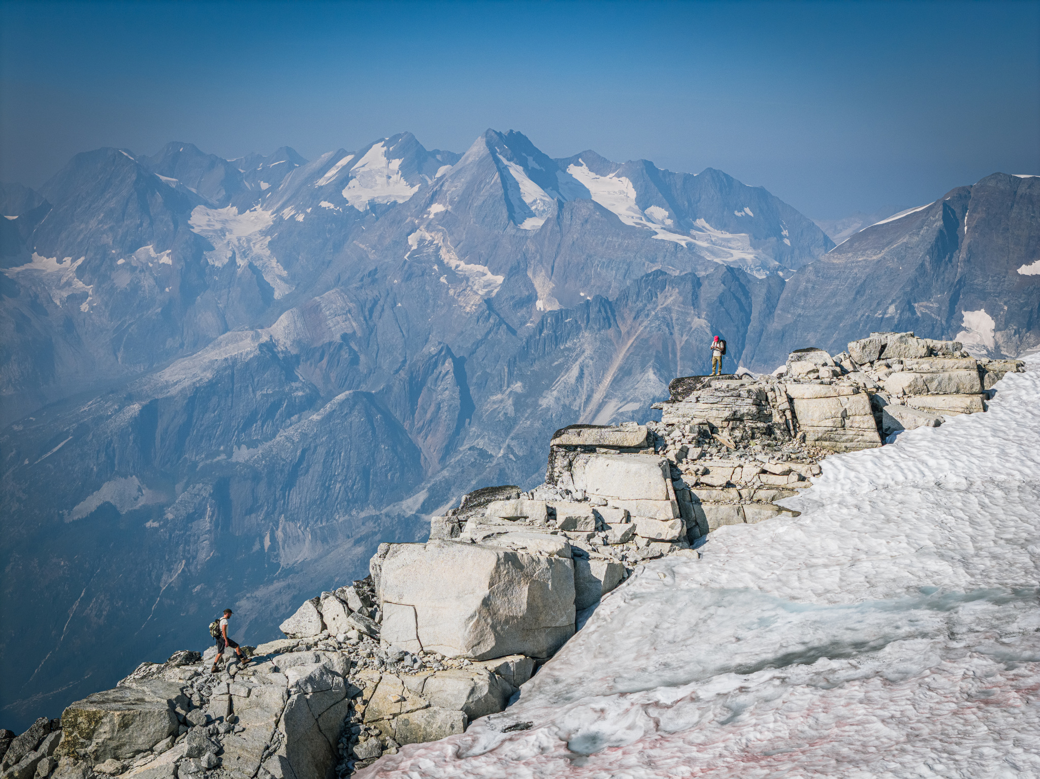 Hikers on granite blocks at the edge of the snow