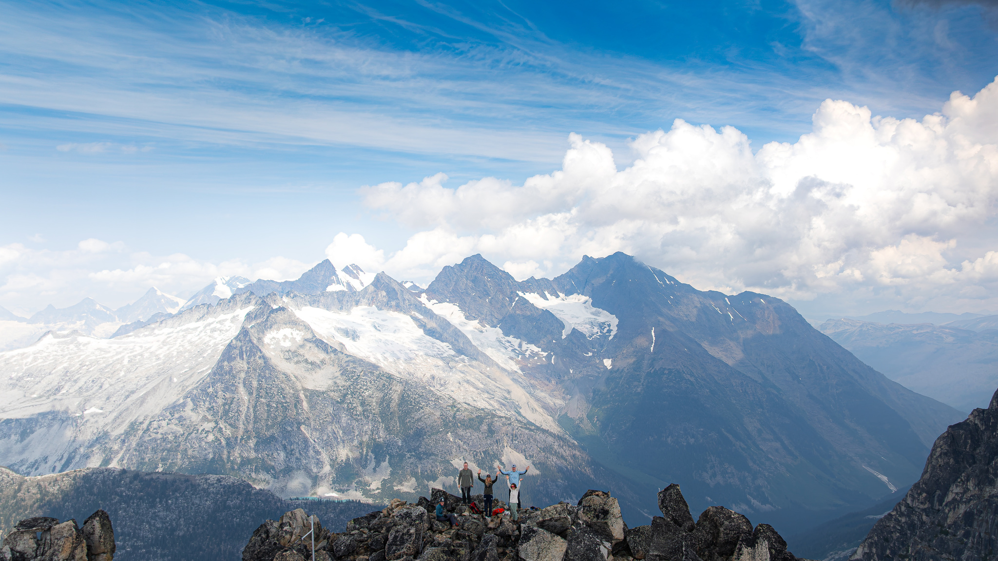Hikers on a rocky summit, glaciers across the valley