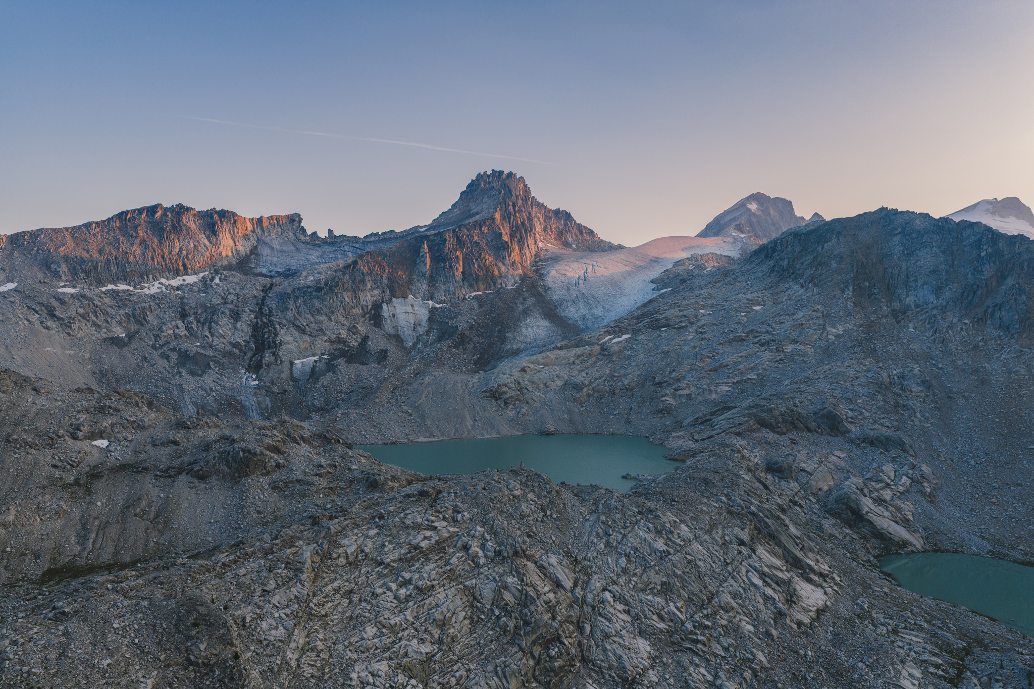 Soft pink light on the peaks above two alpine lakes