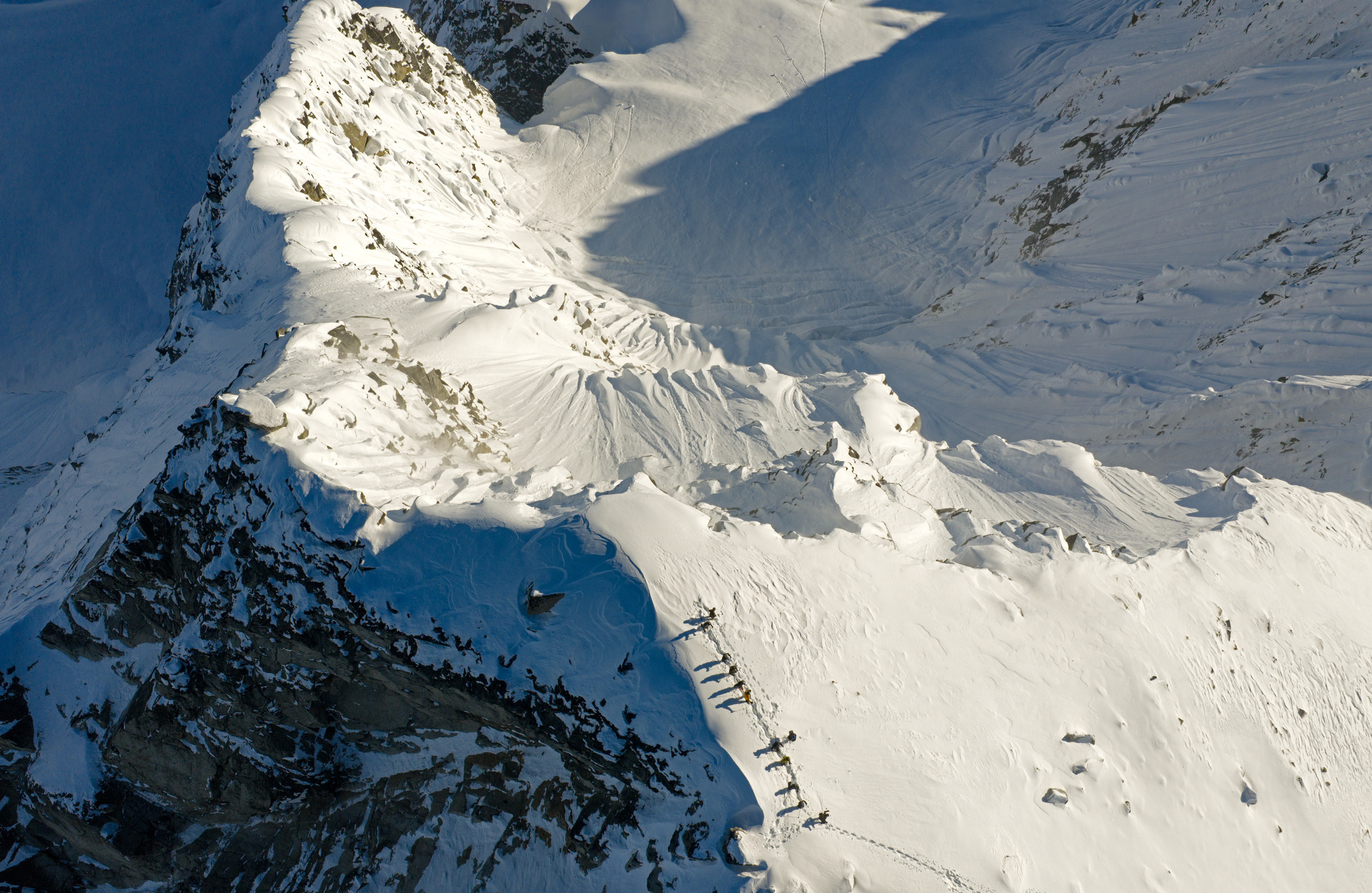 Looking down on a line of ski tourers climbing a steep ridge