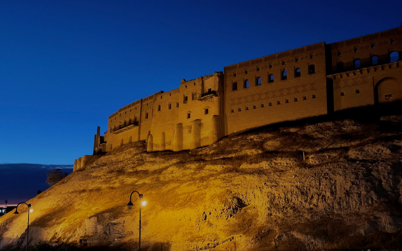 The floodlit walls of the Erbil Citadel above its mound at dusk, Iraqi Kurdistan