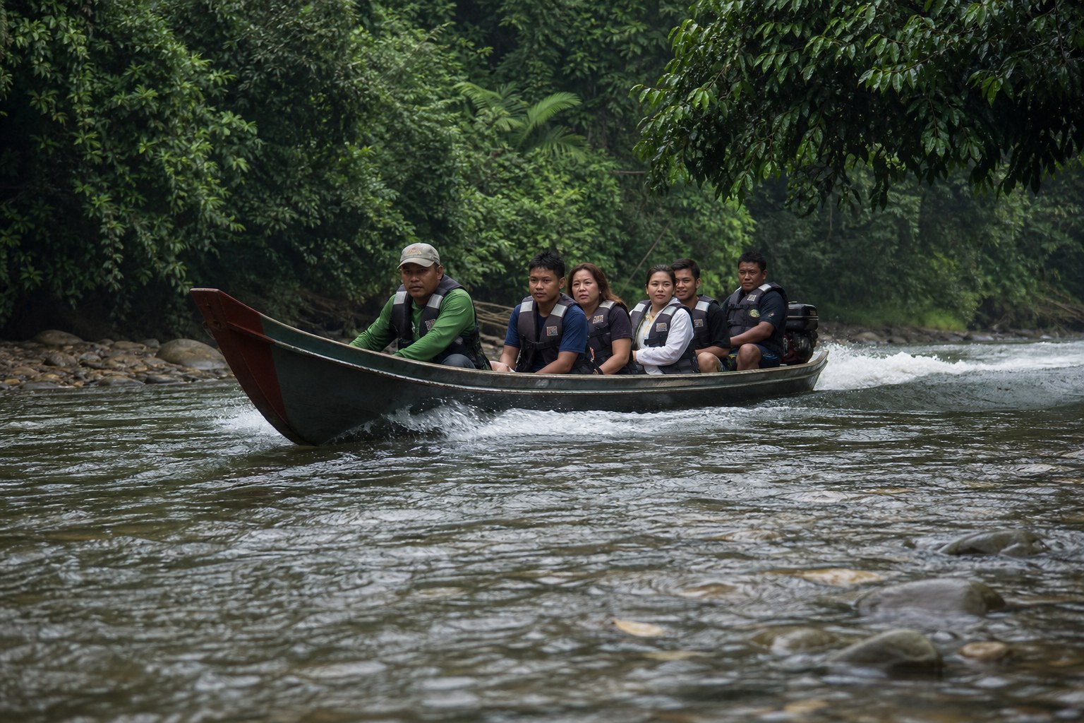 A shallow wooden longboat running the shallows of the Temburong River