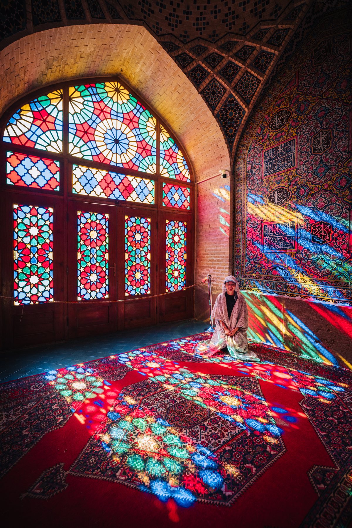 Morning light through the stained glass of the Nasir al-Mulk Pink Mosque in Shiraz, scattering colour across the carpets