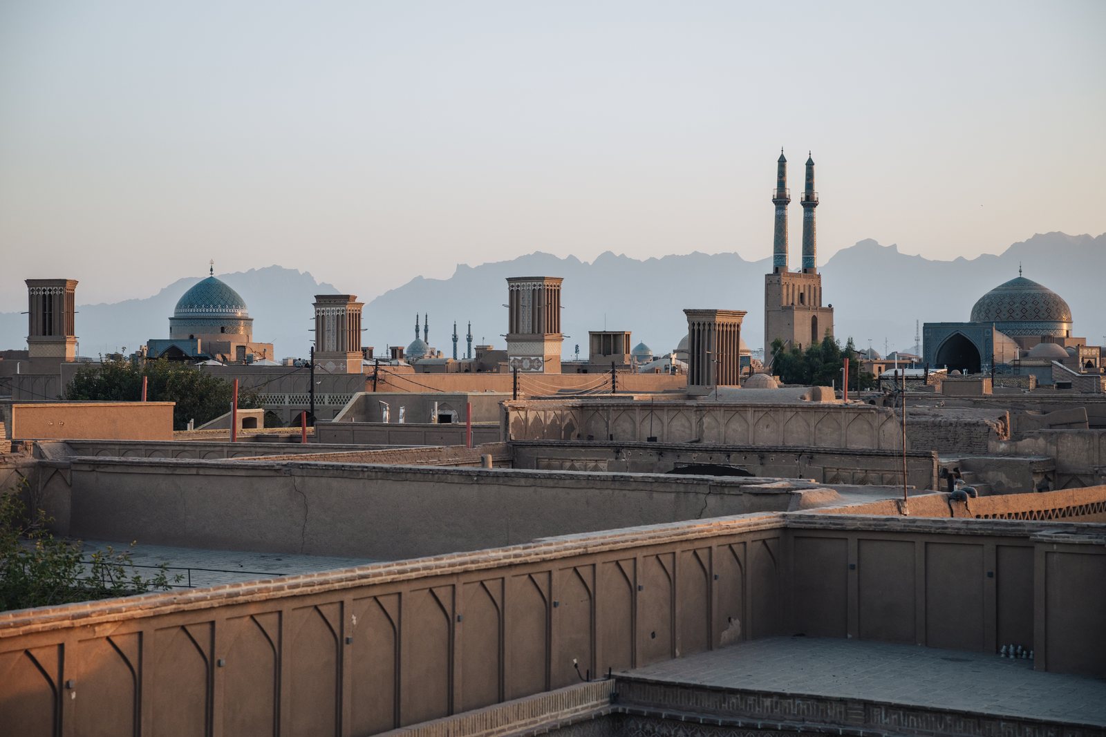 Wind towers, domes and the minarets of the Jameh Mosque above the rooftops of Yazd at dawn