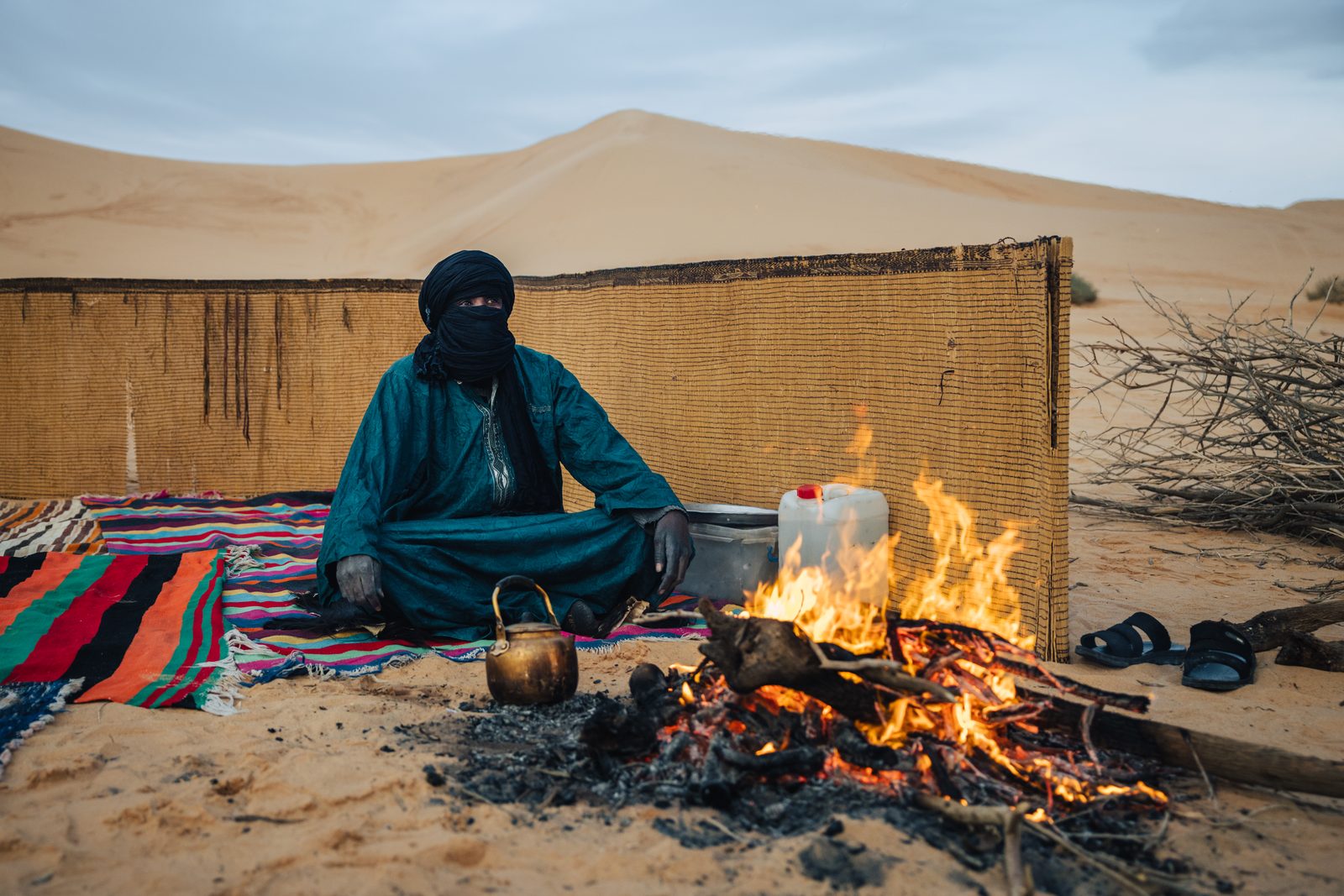 A Tuareg guide brewing tea at a Sahara desert camp at dawn, Libya