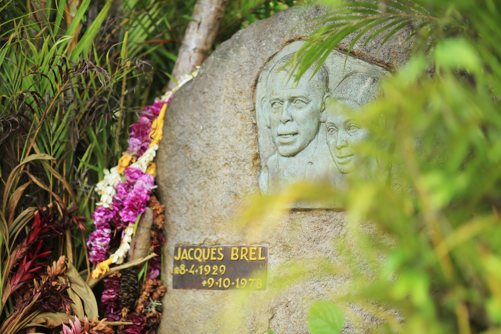 The grave of Jacques Brel at Atuona, a stone with his portrait in relief and a garland of flowers