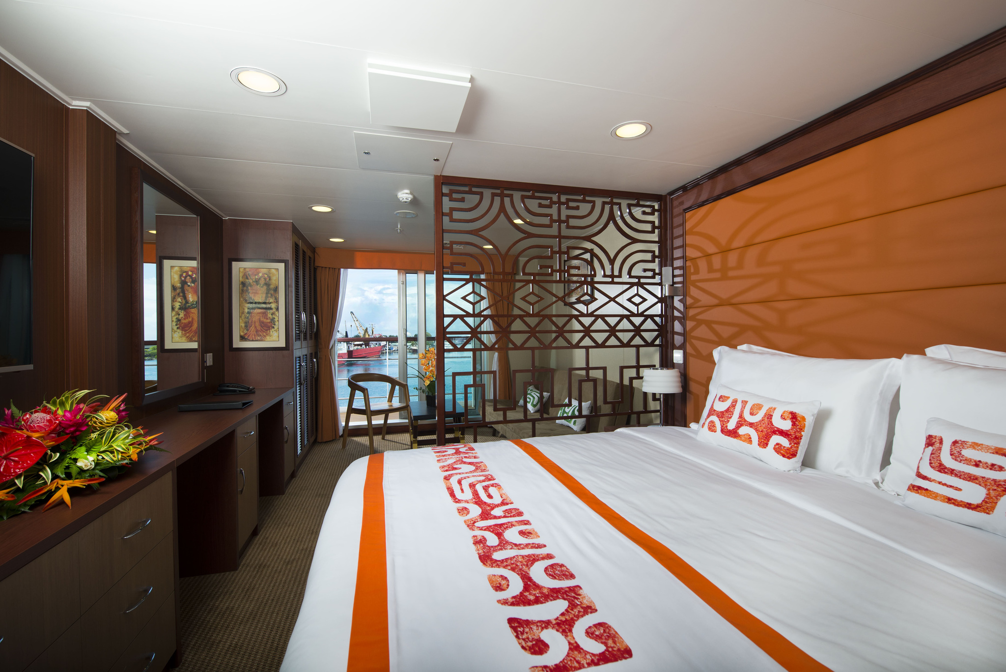 A Premium Suite, with a king bed, a carved screen and the balcony beyond