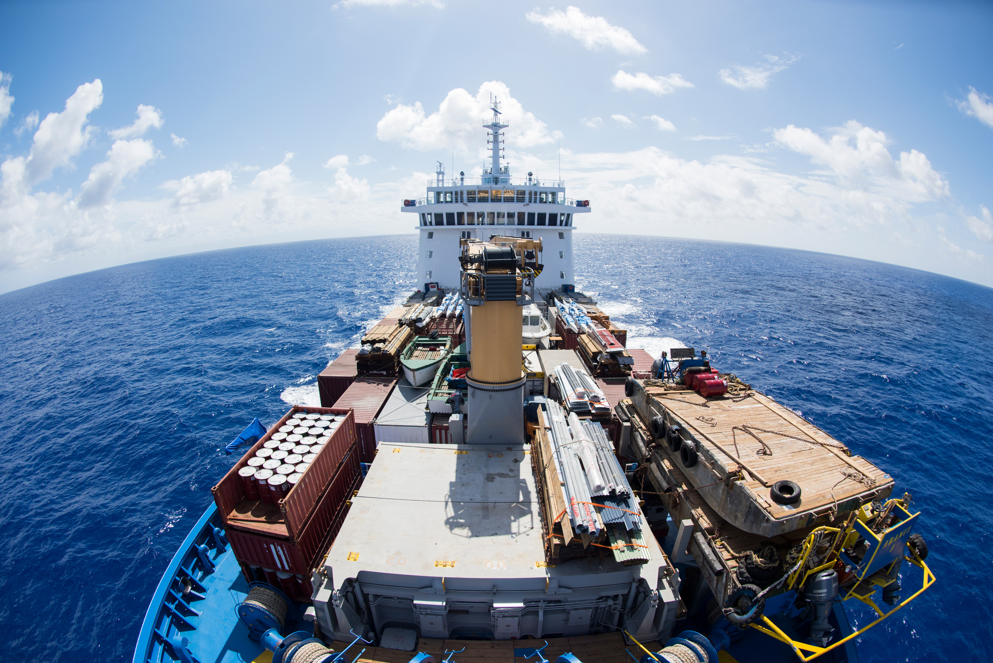 The forward cargo deck, stacked with containers and gear, seen from above the bow