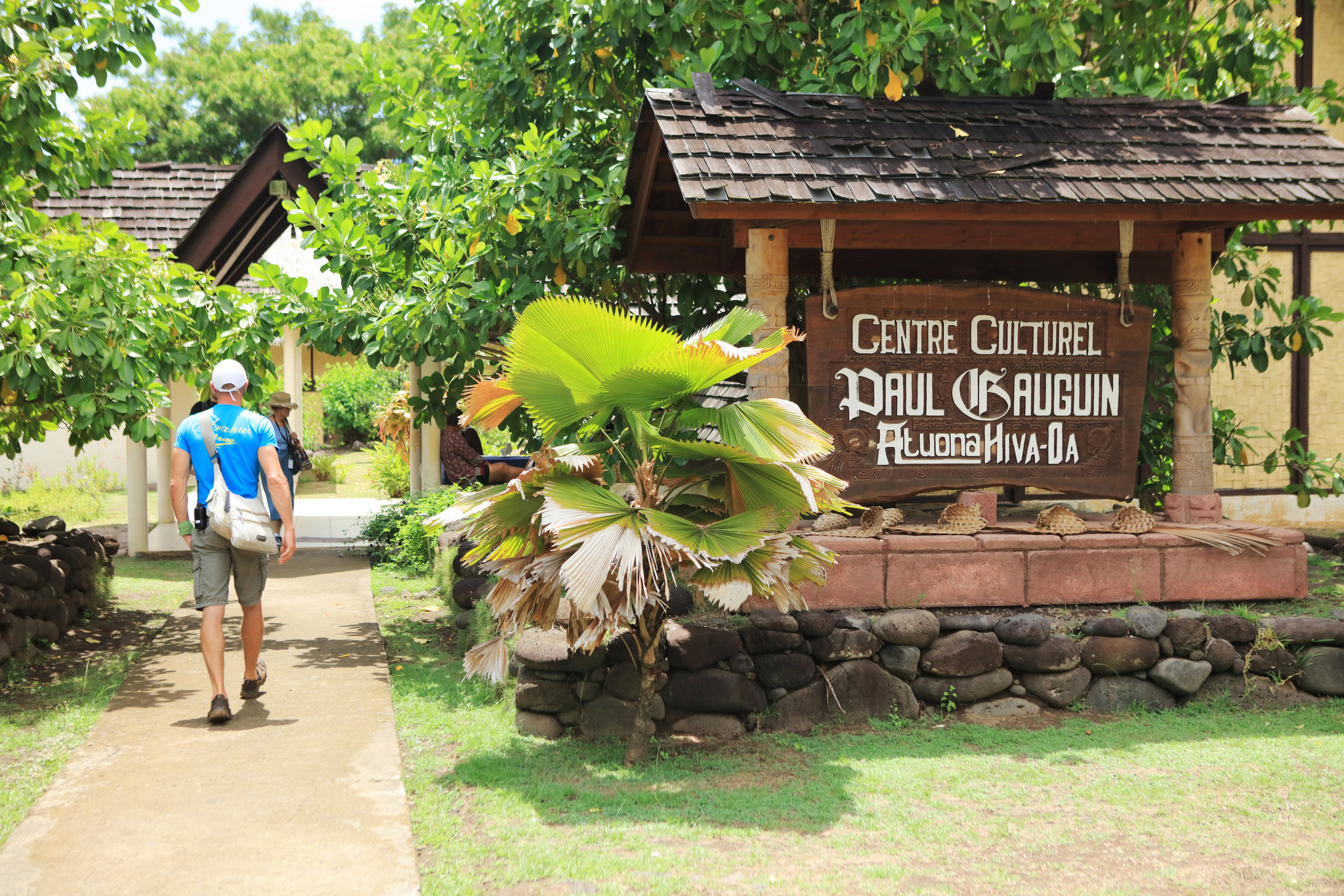 A visitor walking past the carved sign of the Paul Gauguin cultural centre in Atuona