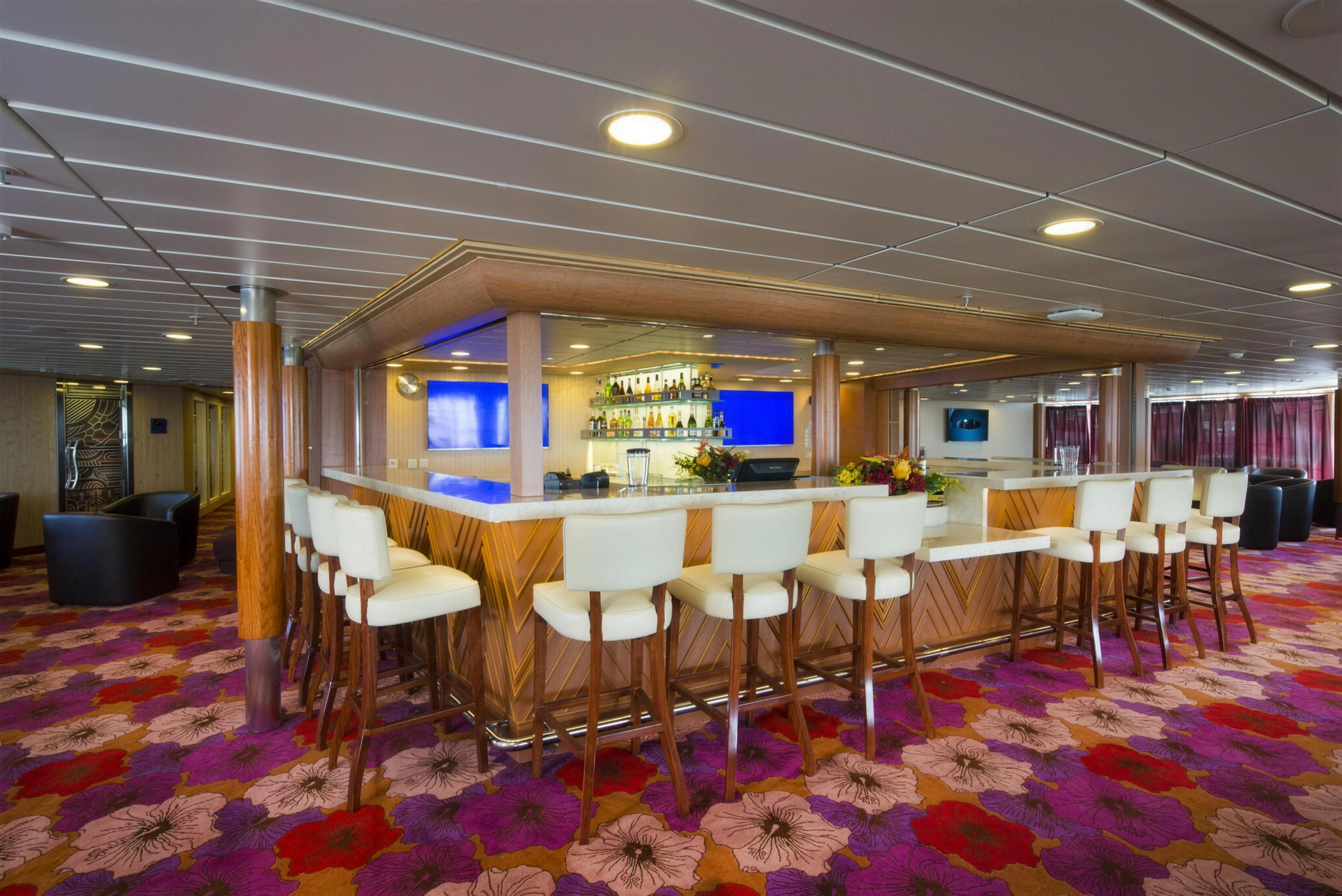 The lounge bar, with white bar stools and a flowered carpet
