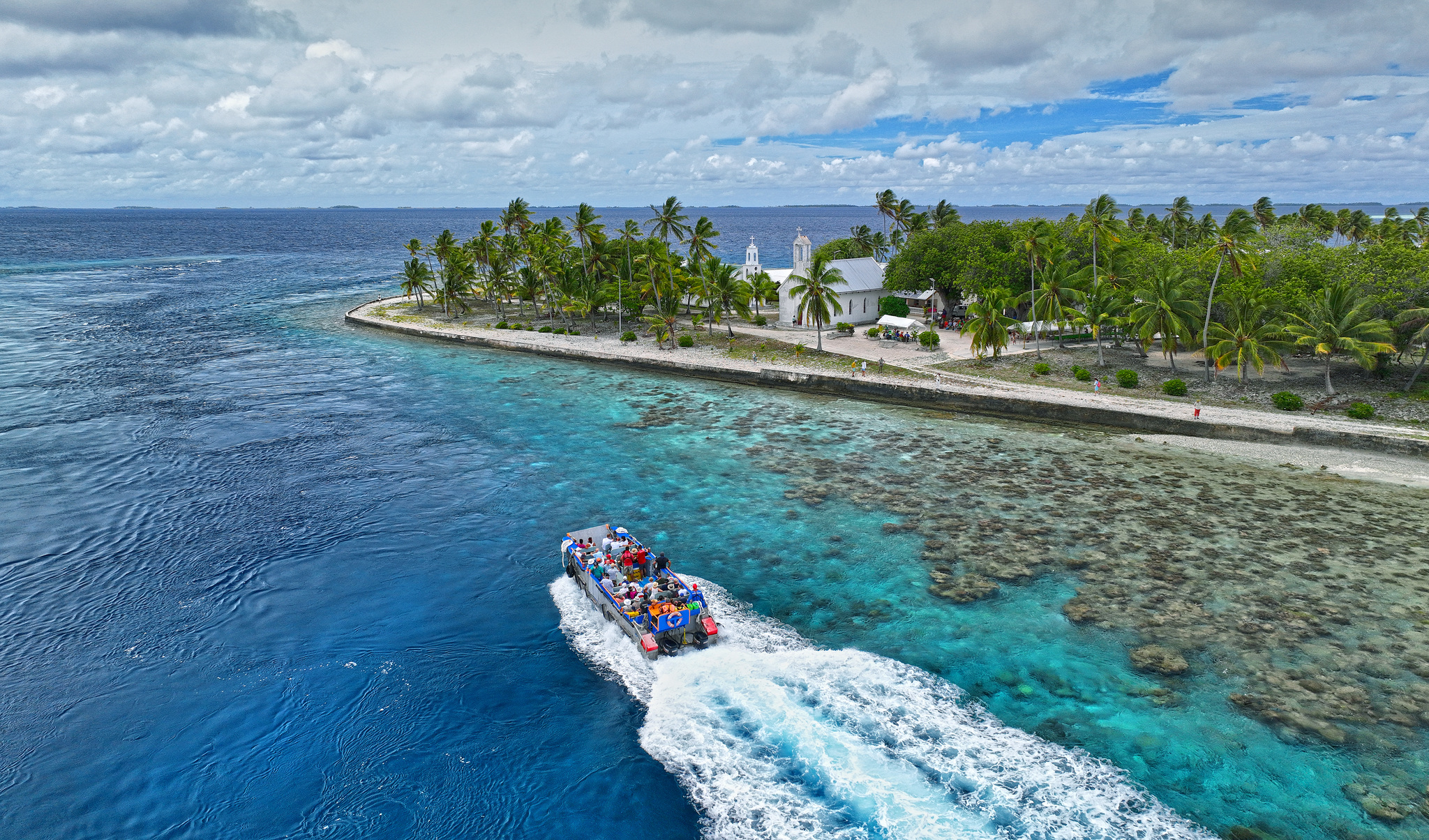 The landing barge carrying passengers toward a village quay on an atoll