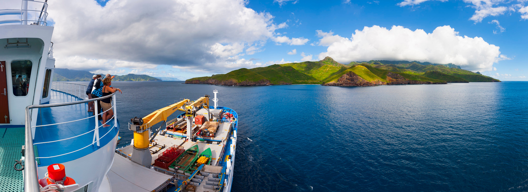 Passengers at the rail as the ship sails past a green island