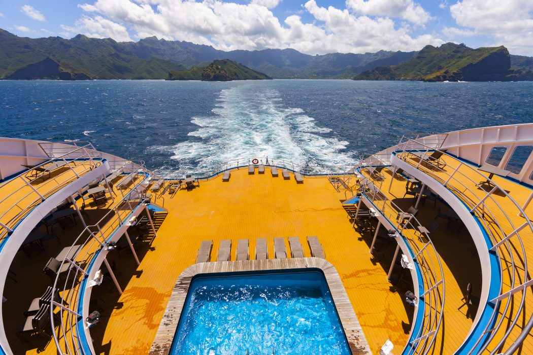 The pool and its deck at the stern, with the wake and green islands behind