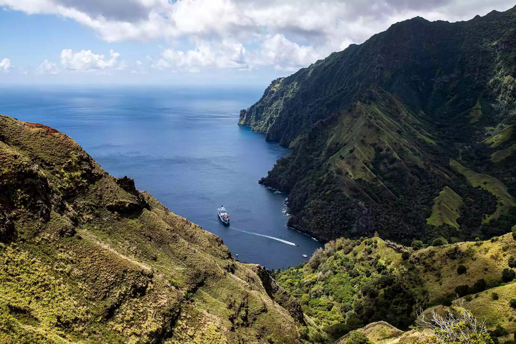 Aranui 5 at anchor in a deep bay on Fatu Hiva, seen from a green ridge above