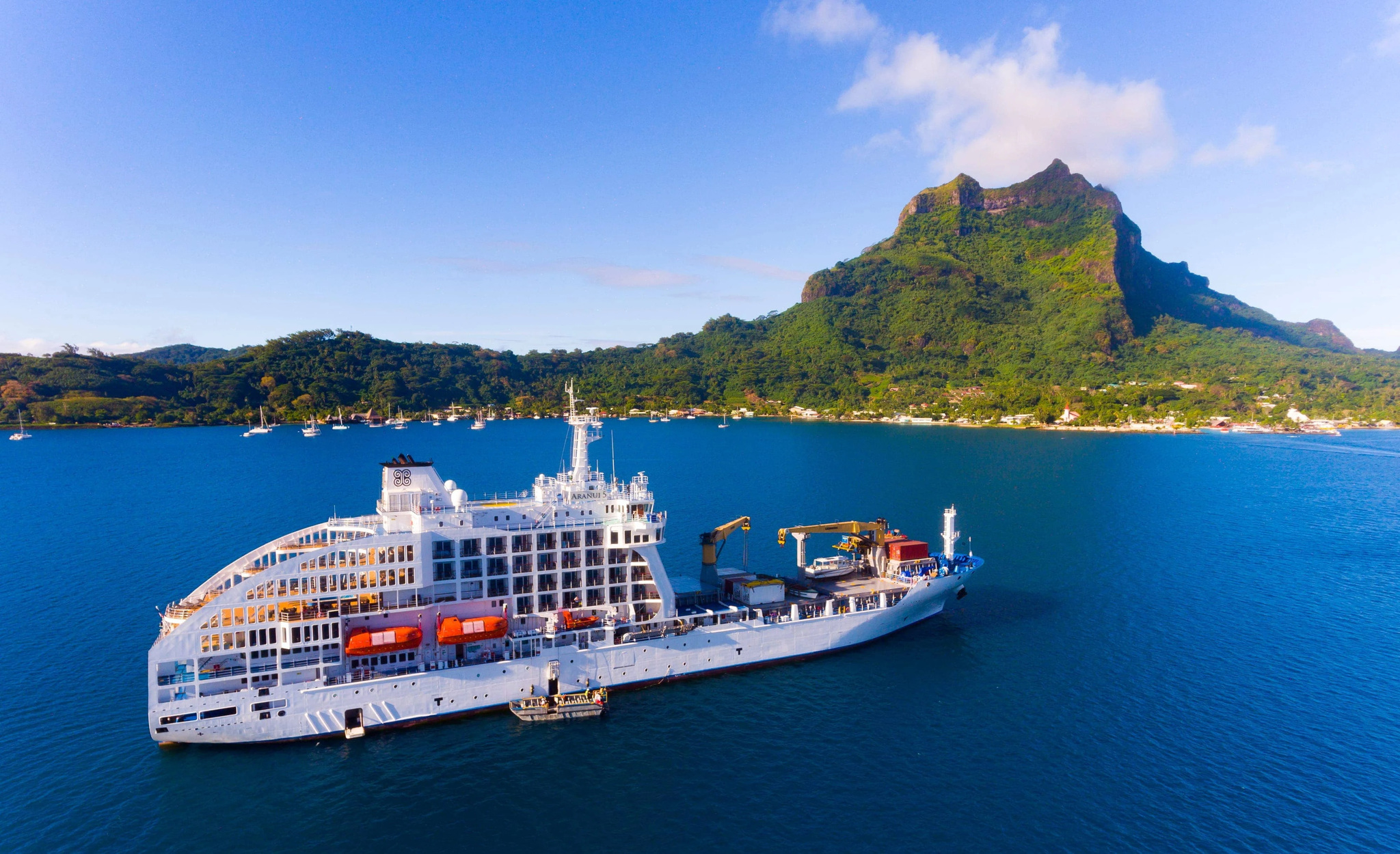 Aranui 5 at anchor off Bora Bora with her landing barge alongside, Mount Otemanu behind