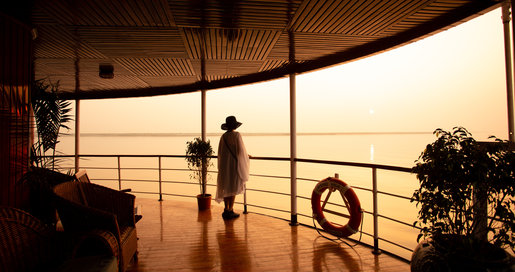 A guest at the rail of the bow deck at sunset