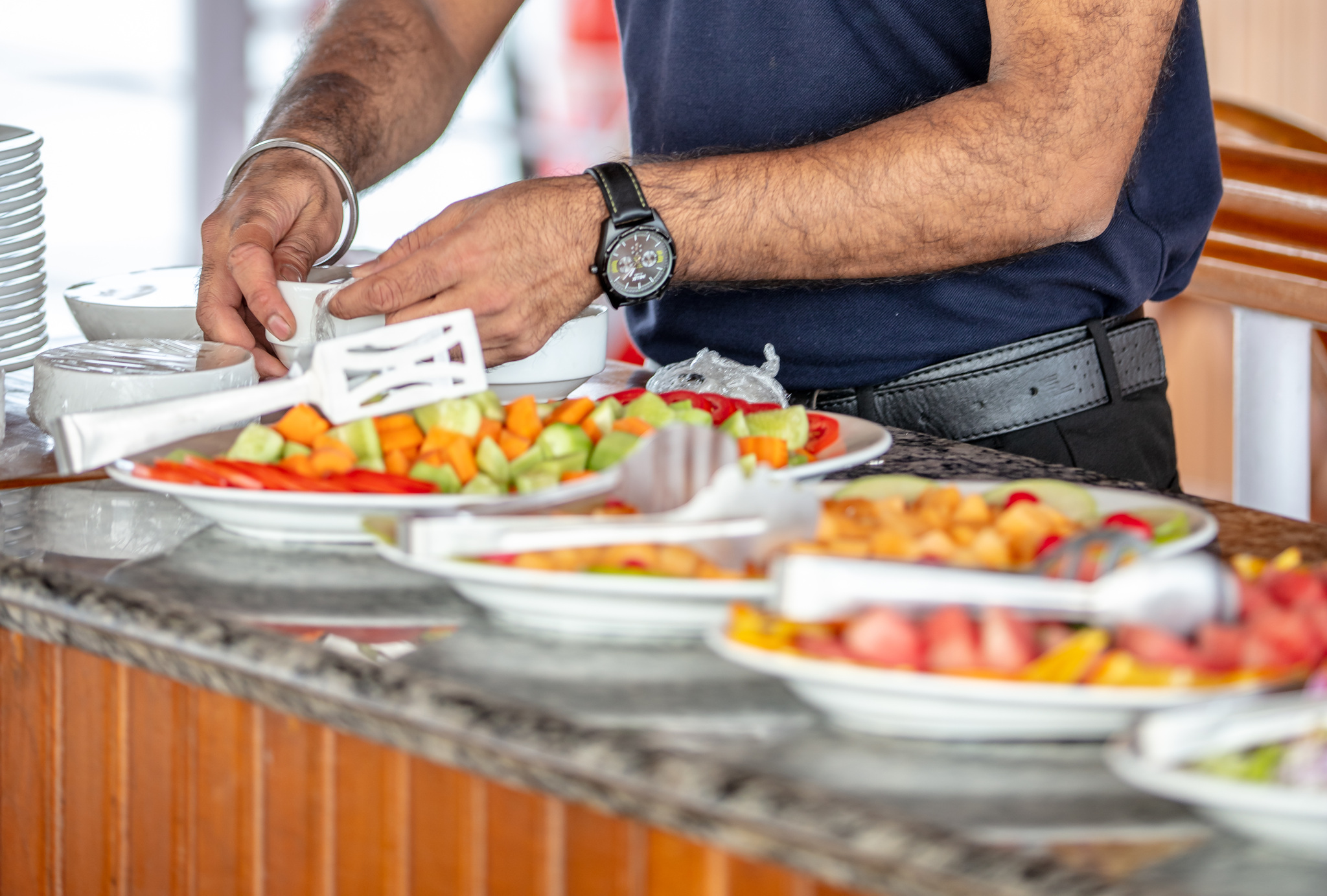 Platters of cut fruit and salad being set out at the buffet
