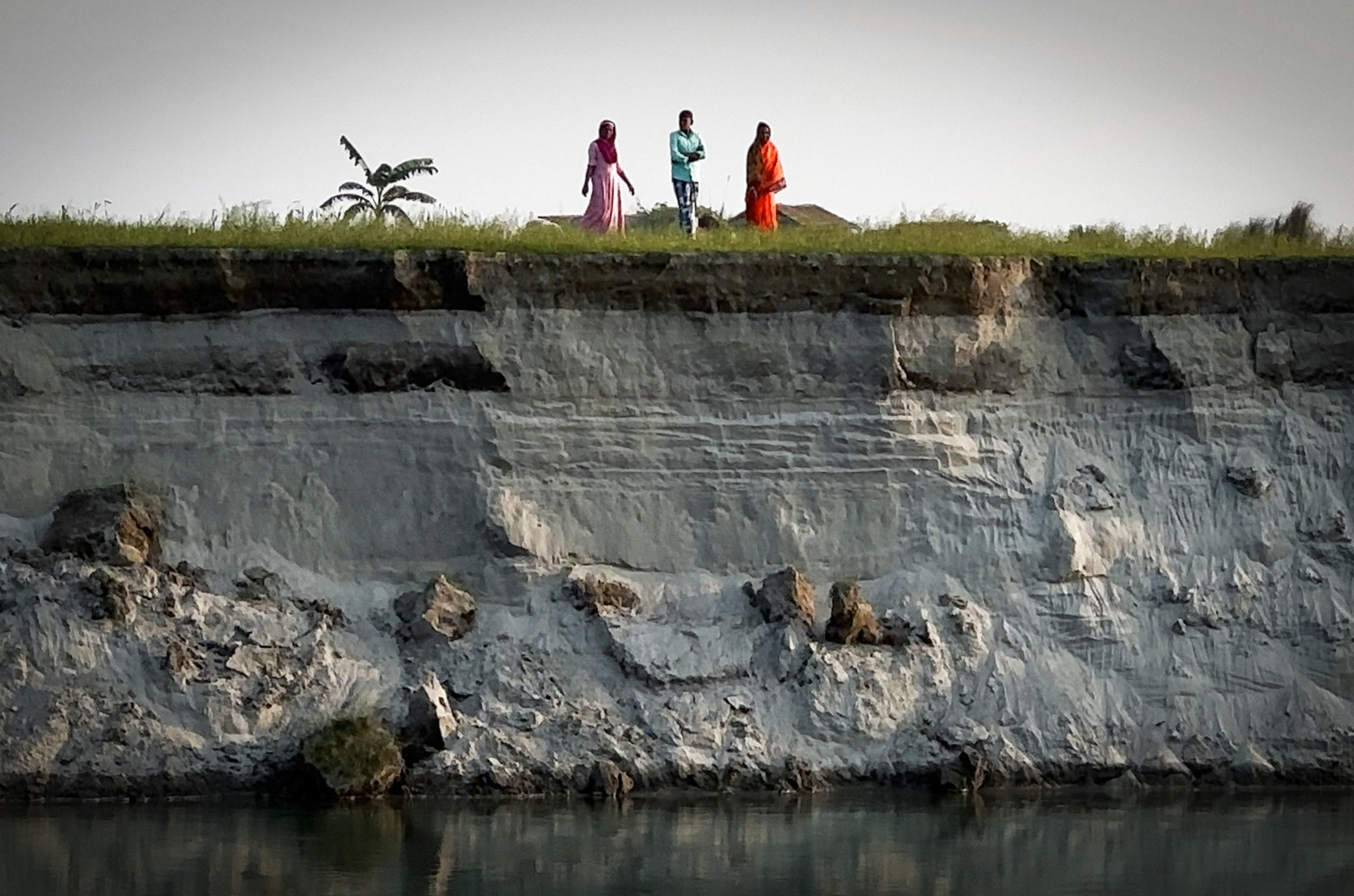 Villagers on top of a high, eroded riverbank