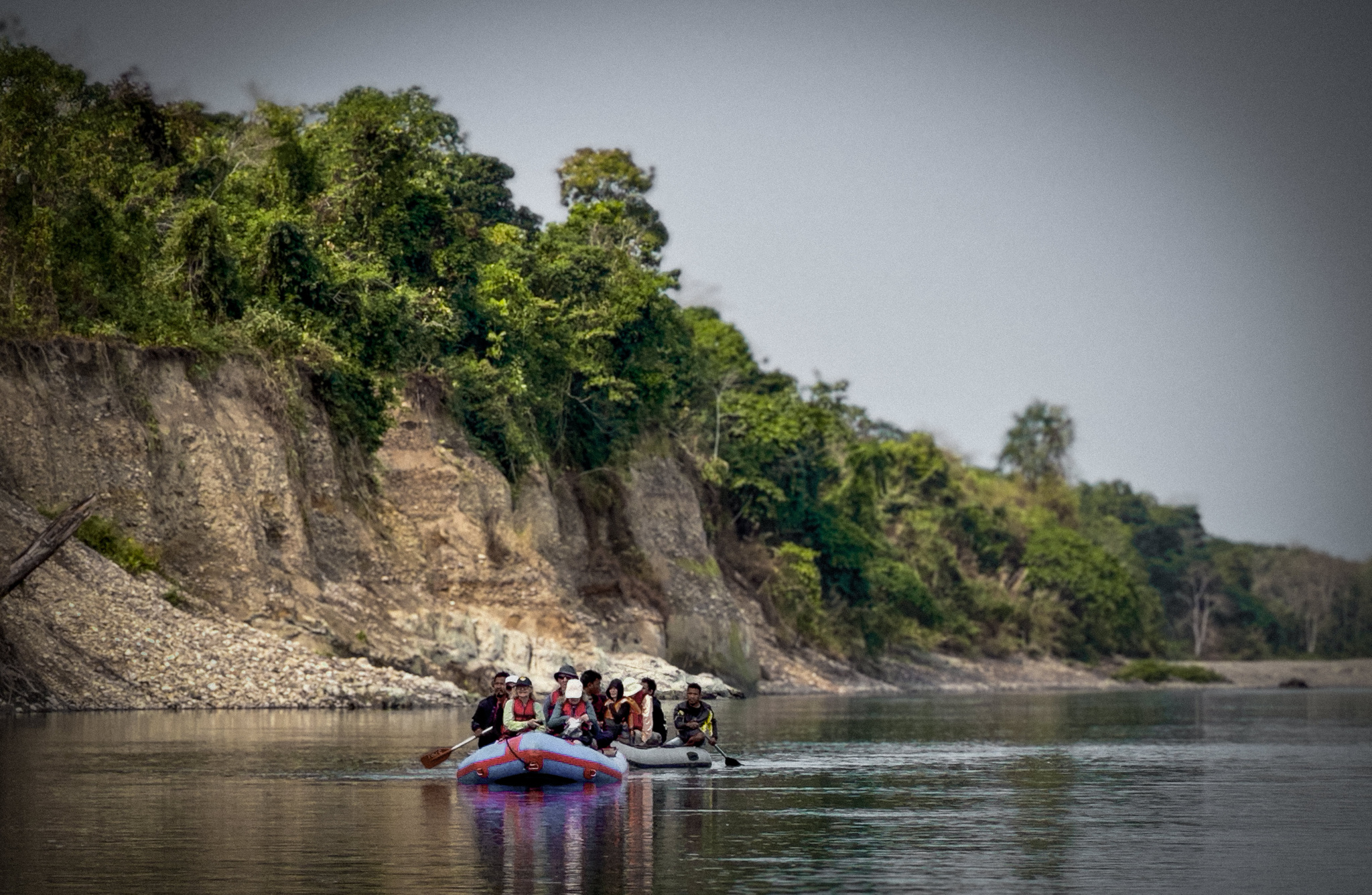 Rafts drifting below a forested bluff at Nameri