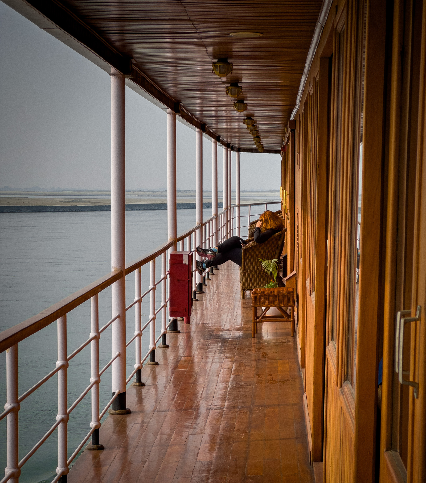 The teak promenade deck of RV Kindat Pandaw, with the river alongside
