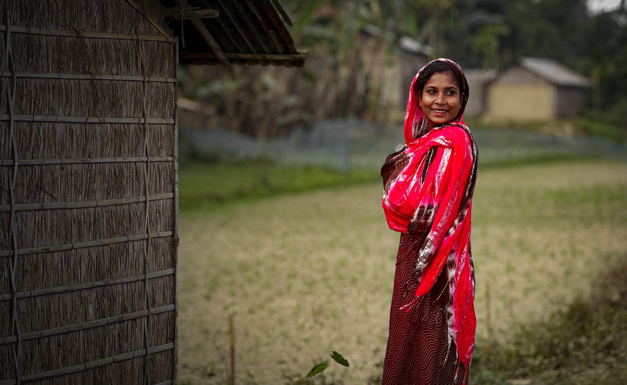 A woman in a red shawl beside a field