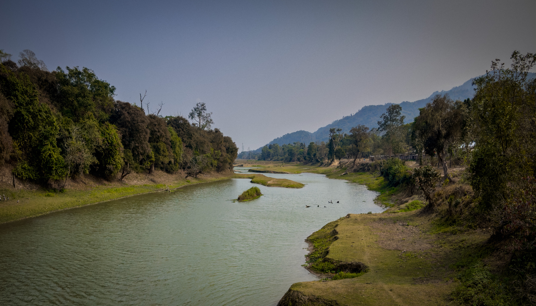 A narrow channel between green banks, with hills beyond