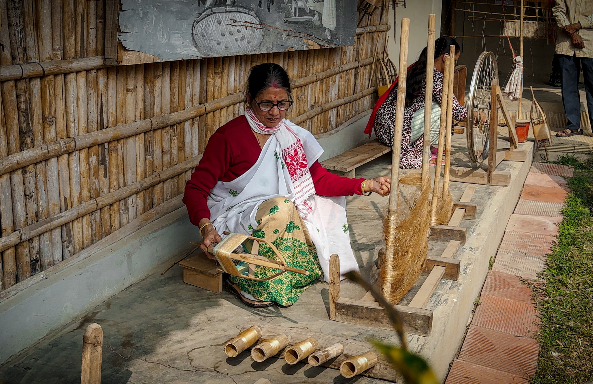 A woman spinning silk thread onto bamboo bobbins