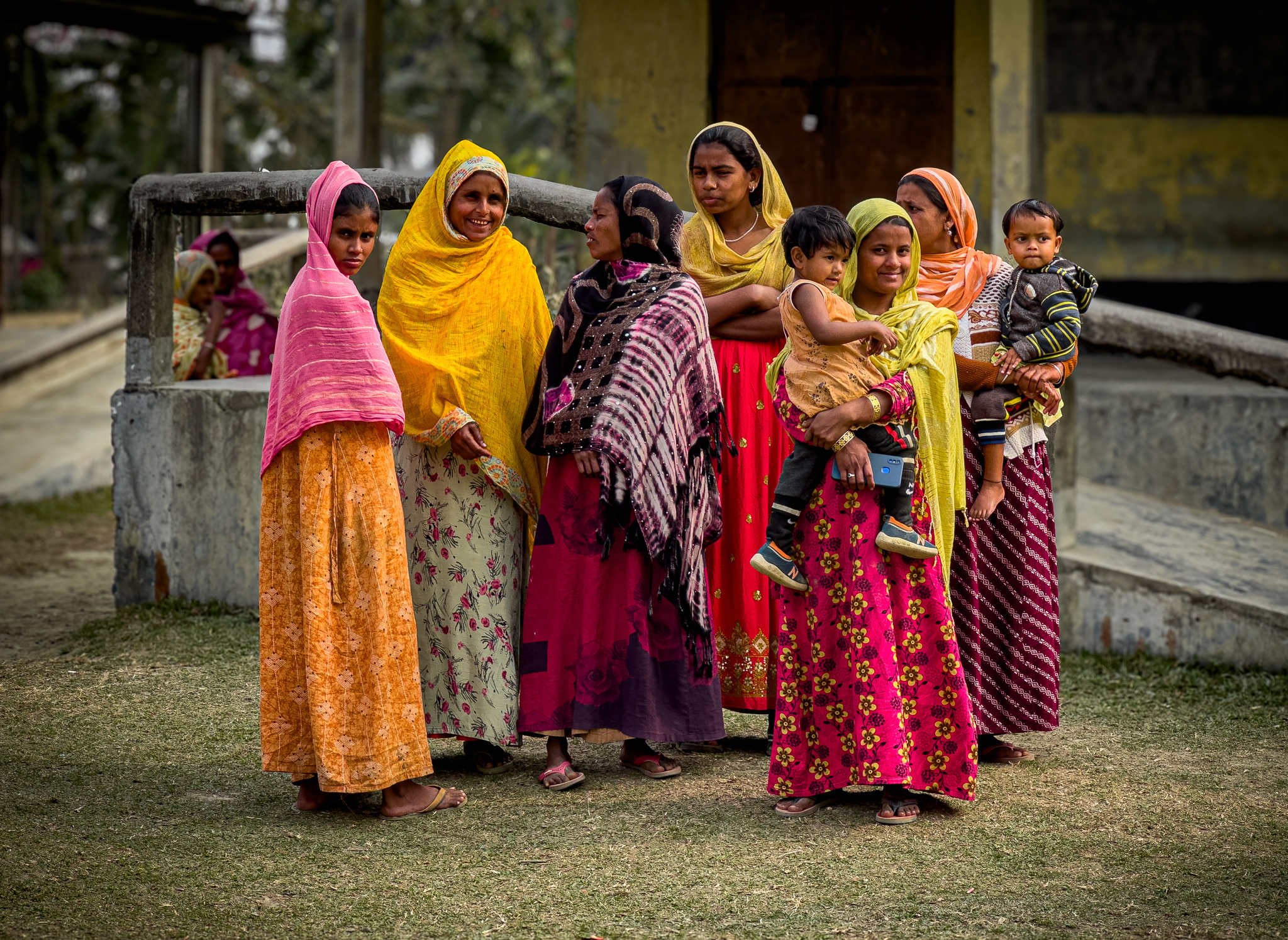 Women and children in bright saris outside a village house