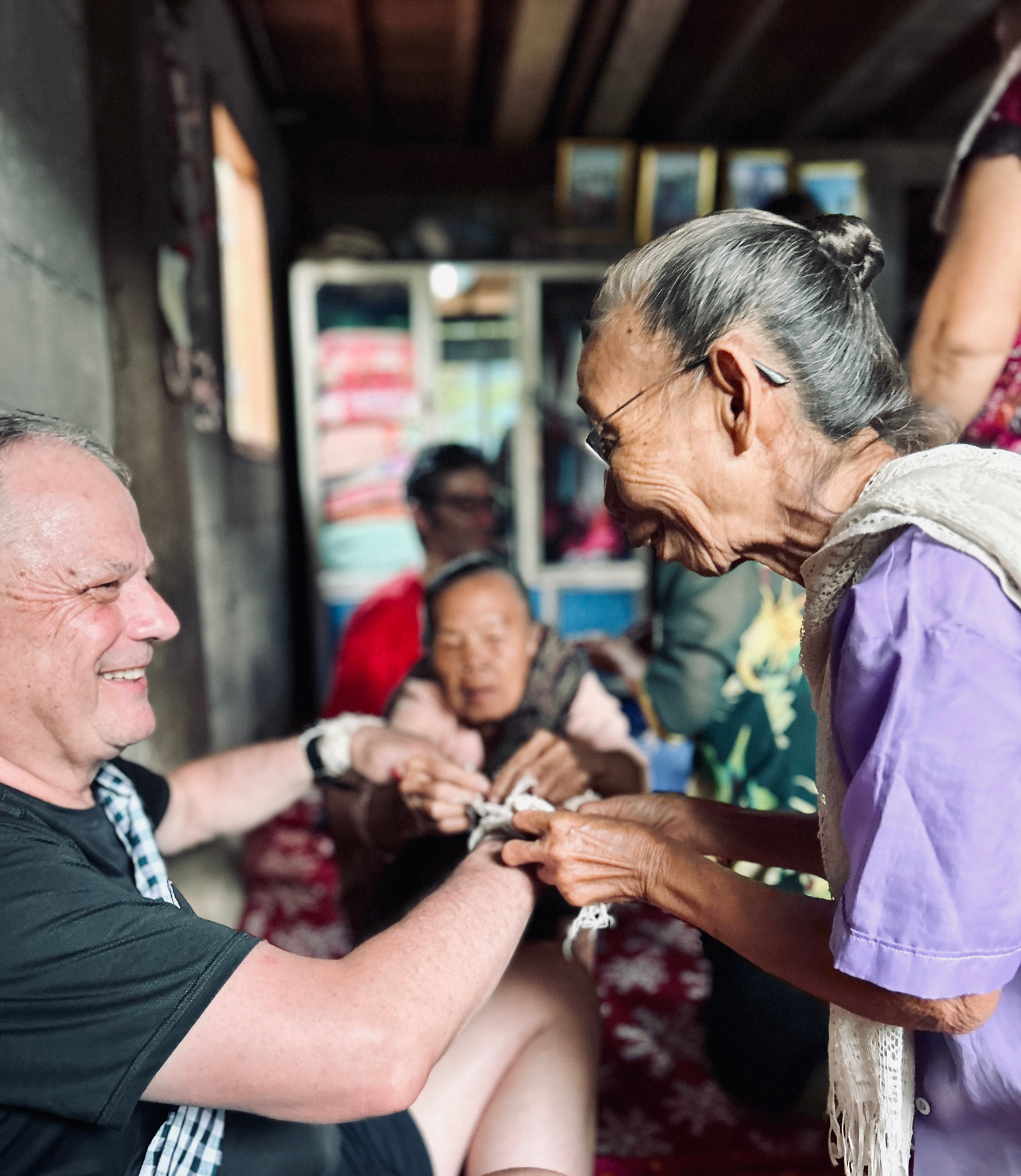 A village elder ties a blessing string at a Baci ceremony