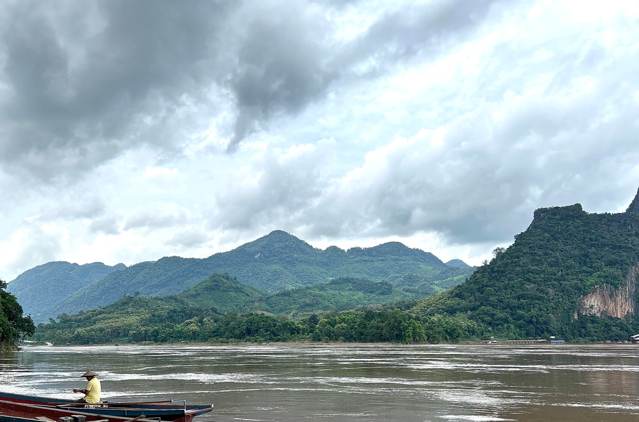 A boatman on the Mekong below the limestone cliffs