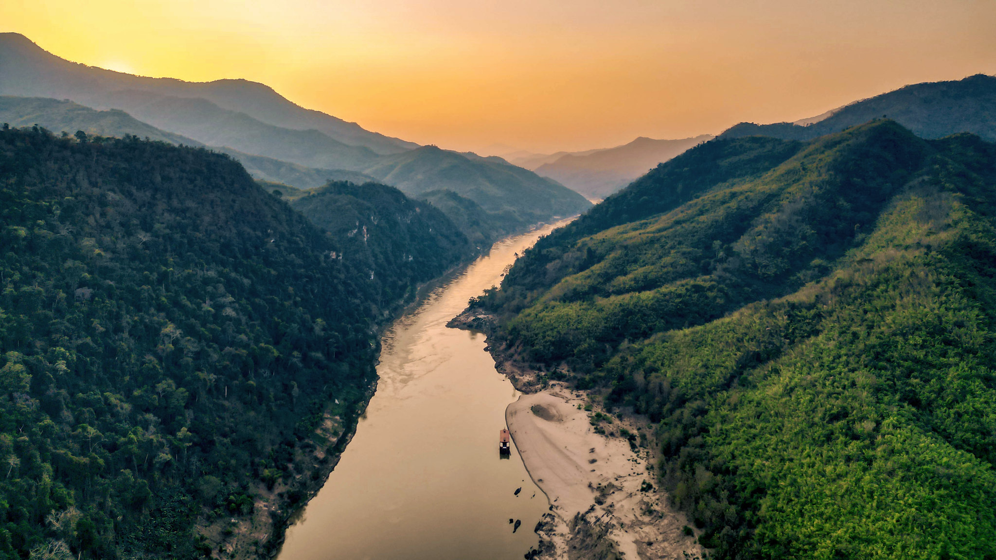 The Mekong winding between forested hills at dusk, from the air