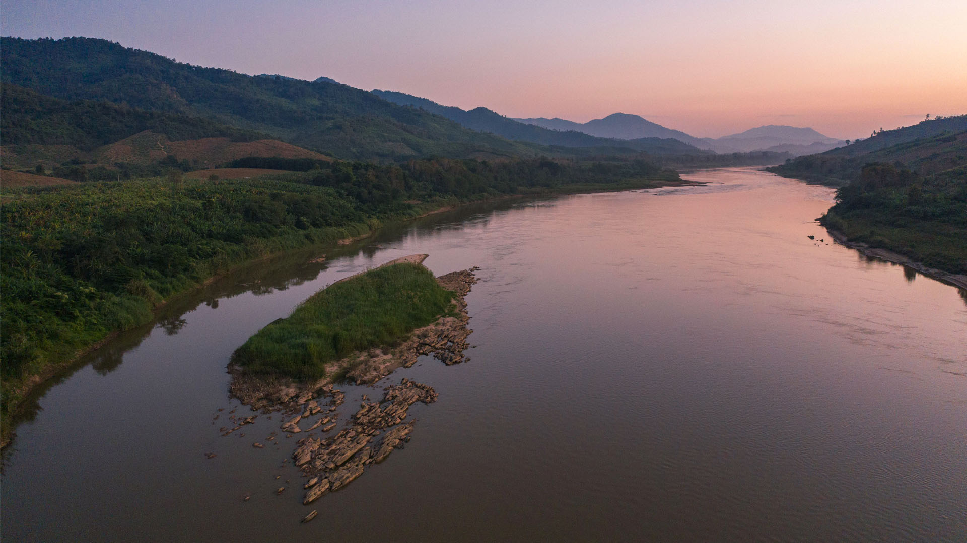 The Mekong at dusk, with a rocky island in midstream