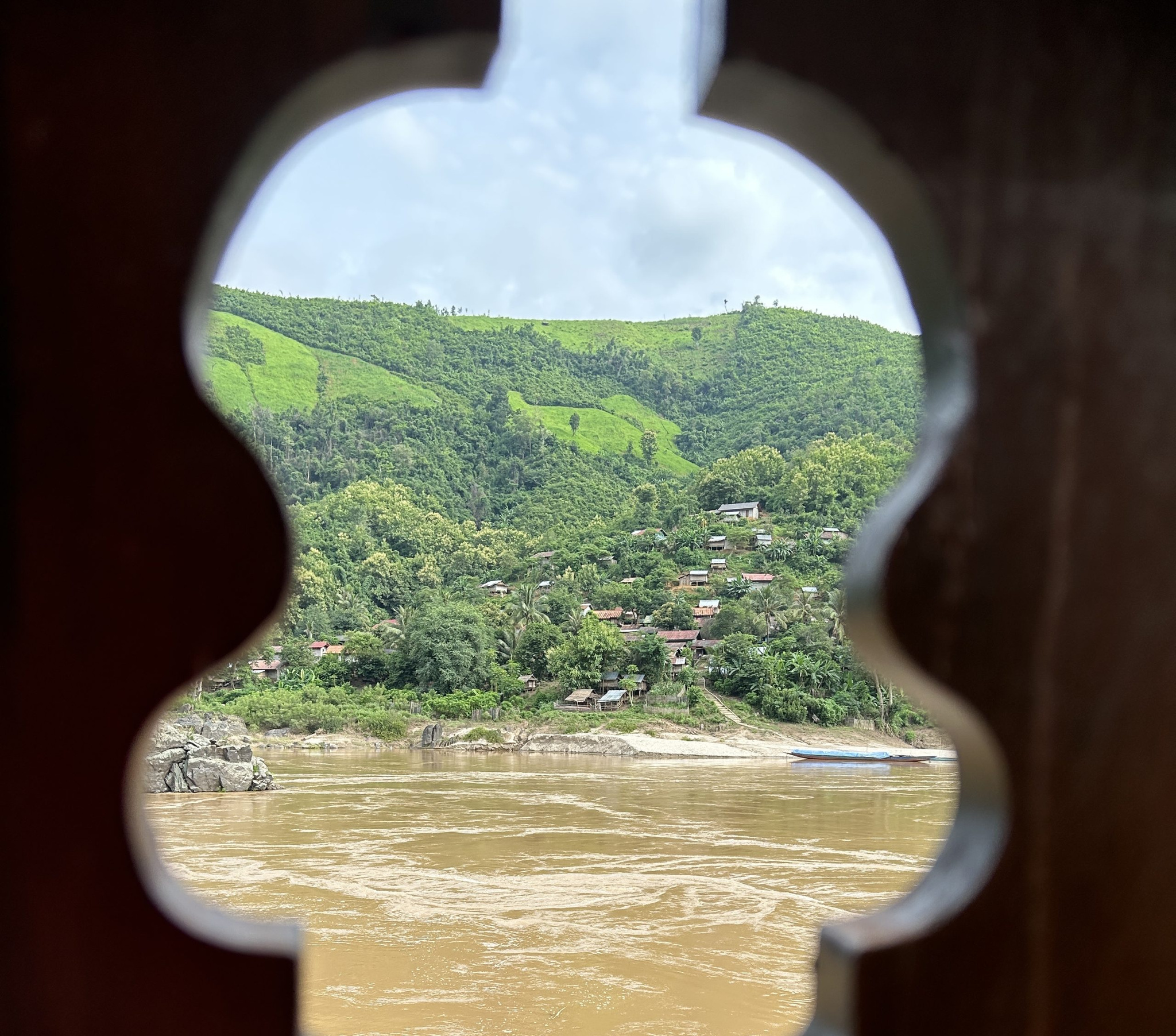 The Mekong framed by a carved opening in the ship's wooden rail