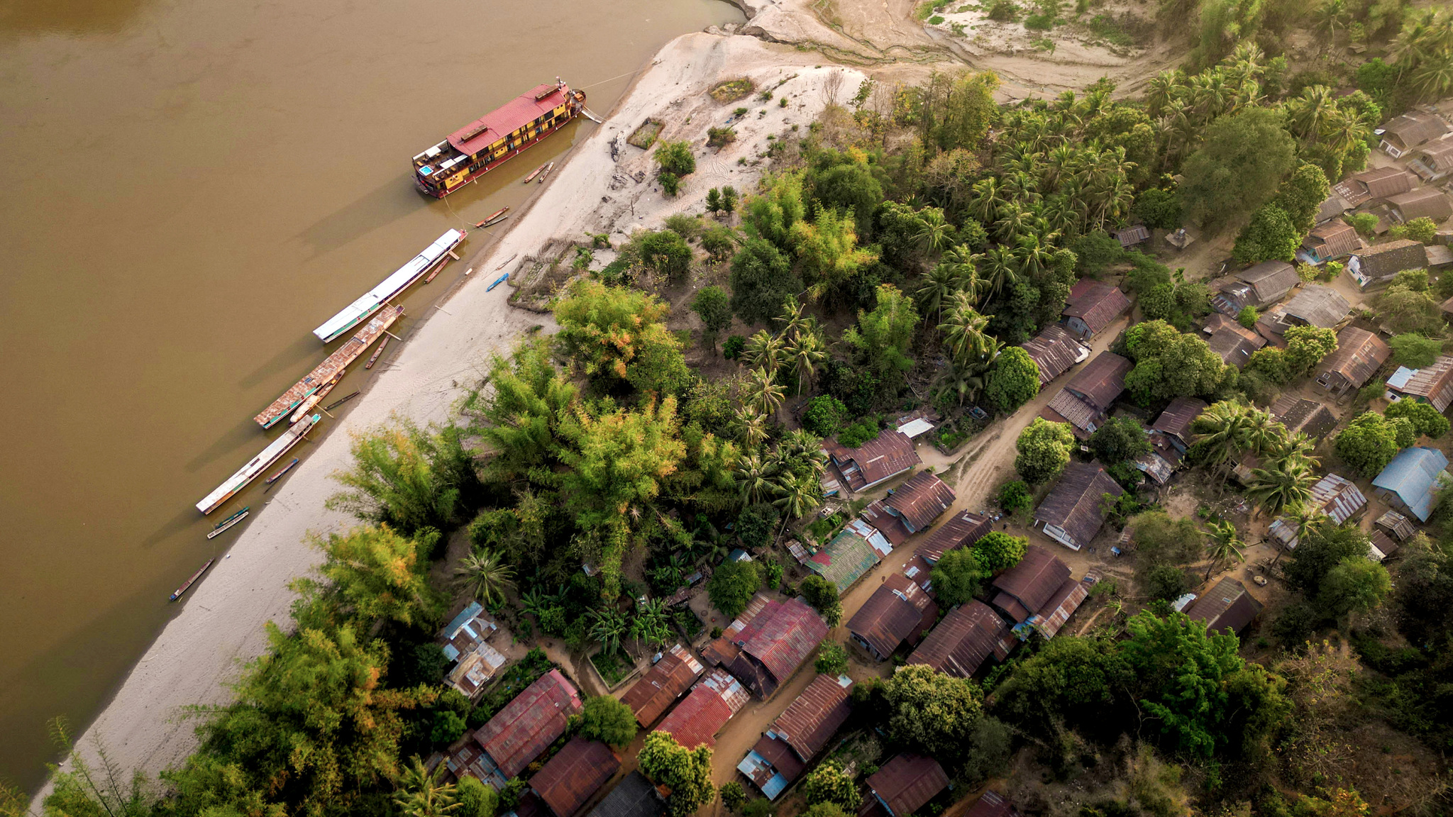 A riverside village from the air, with boats pulled up on the bank