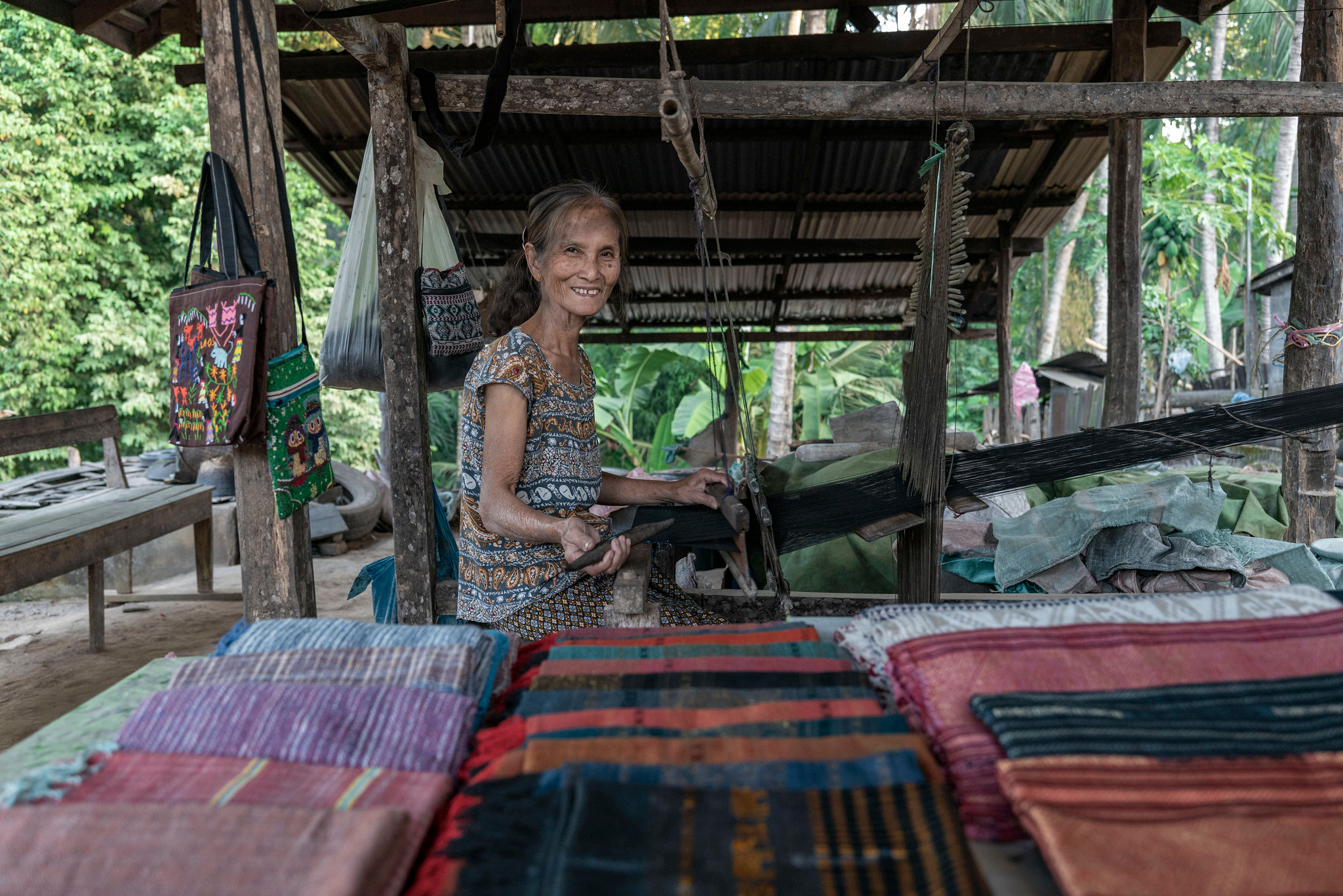 A weaver at her loom, with her cloth for sale