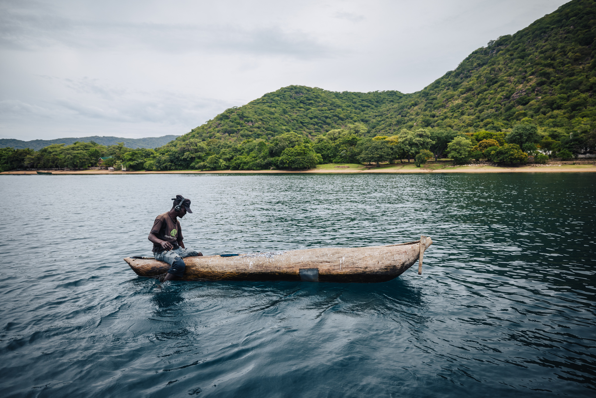 A fisherman in a dugout canoe off Cape Maclear, the green hills of the cape behind