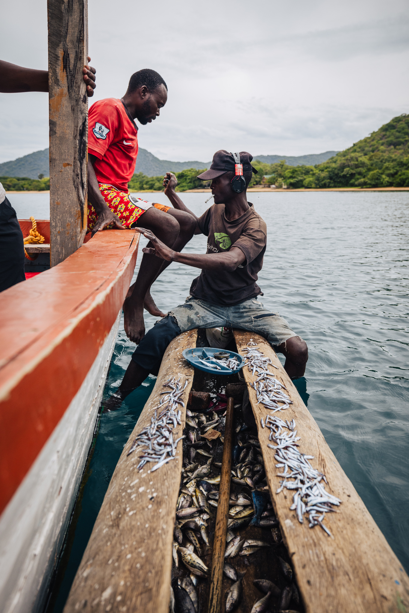 Fishermen with a catch of small fish in their dugout