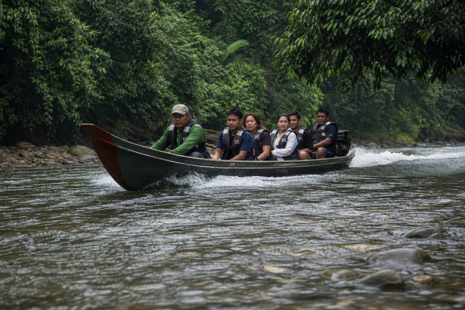 A shallow wooden longboat running the shallows of the Temburong River