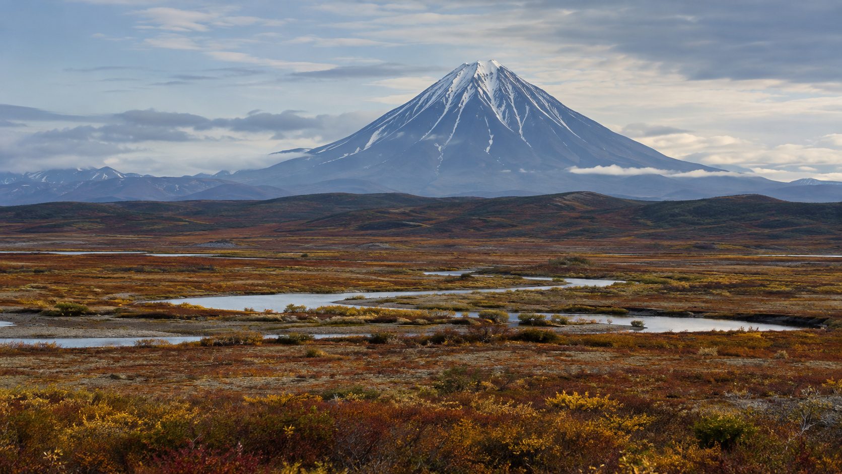 Snow-streaked Kamchatka volcano above autumn tundra