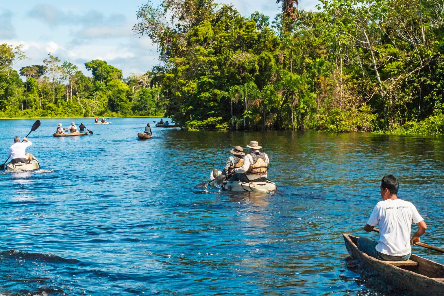 Kayaks, a skiff and a dugout canoe on a lake fringed with forest