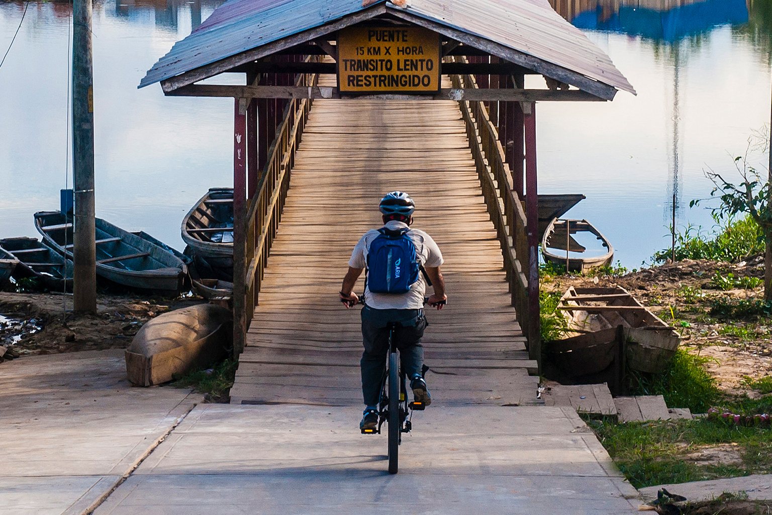 A guest cycling across a wooden jetty to the village