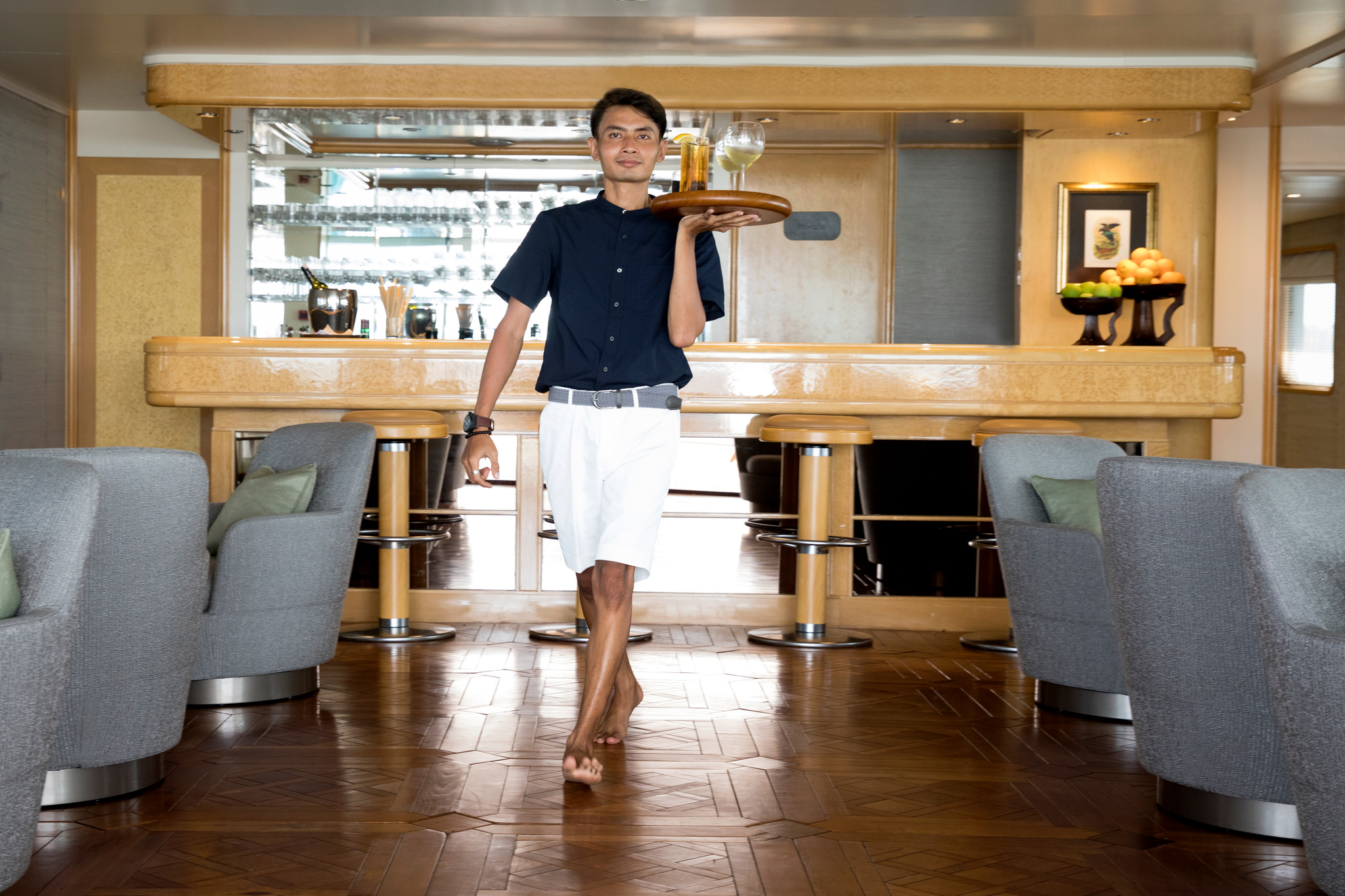 A crew member carrying a tray of drinks past the bar in the lounge