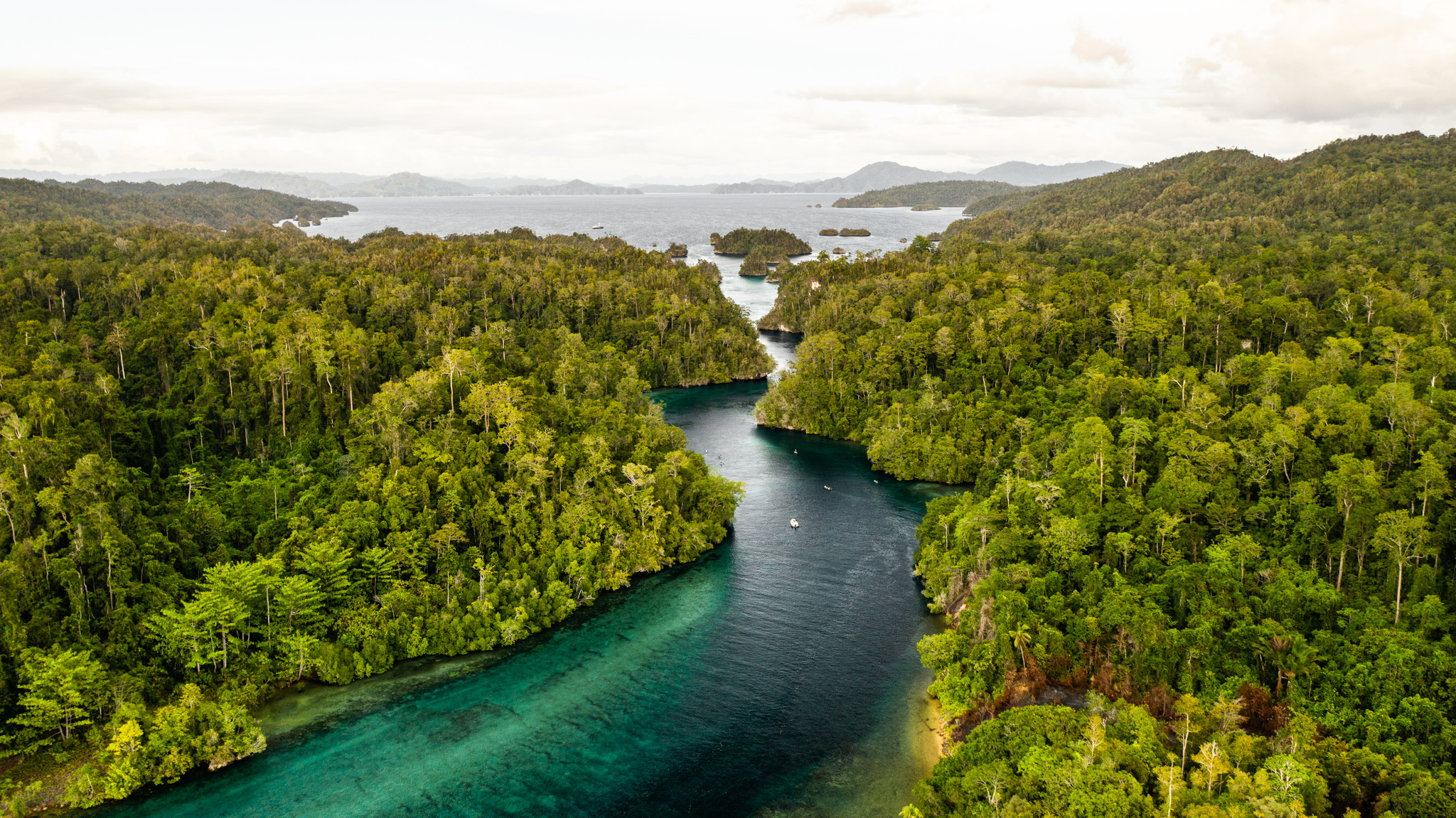 A turquoise channel winding between forested islands toward the open sea