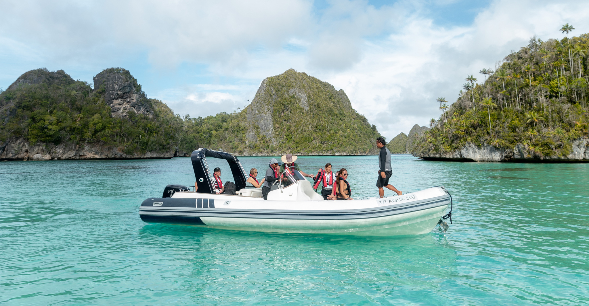 Guests in life jackets in a tender among steep forested islets in Kabui Bay