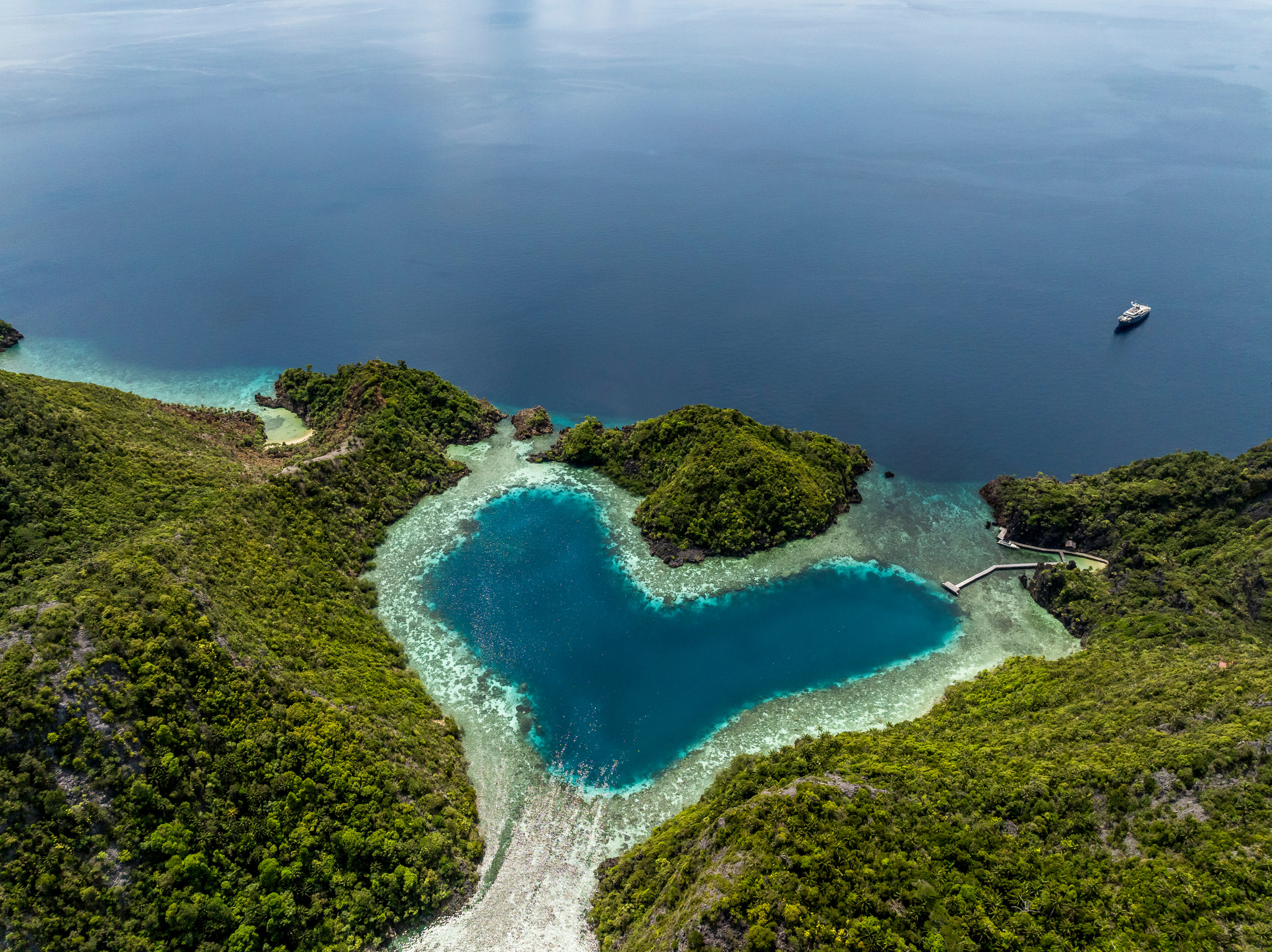 A heart-shaped blue lagoon among forested hills in Misool
