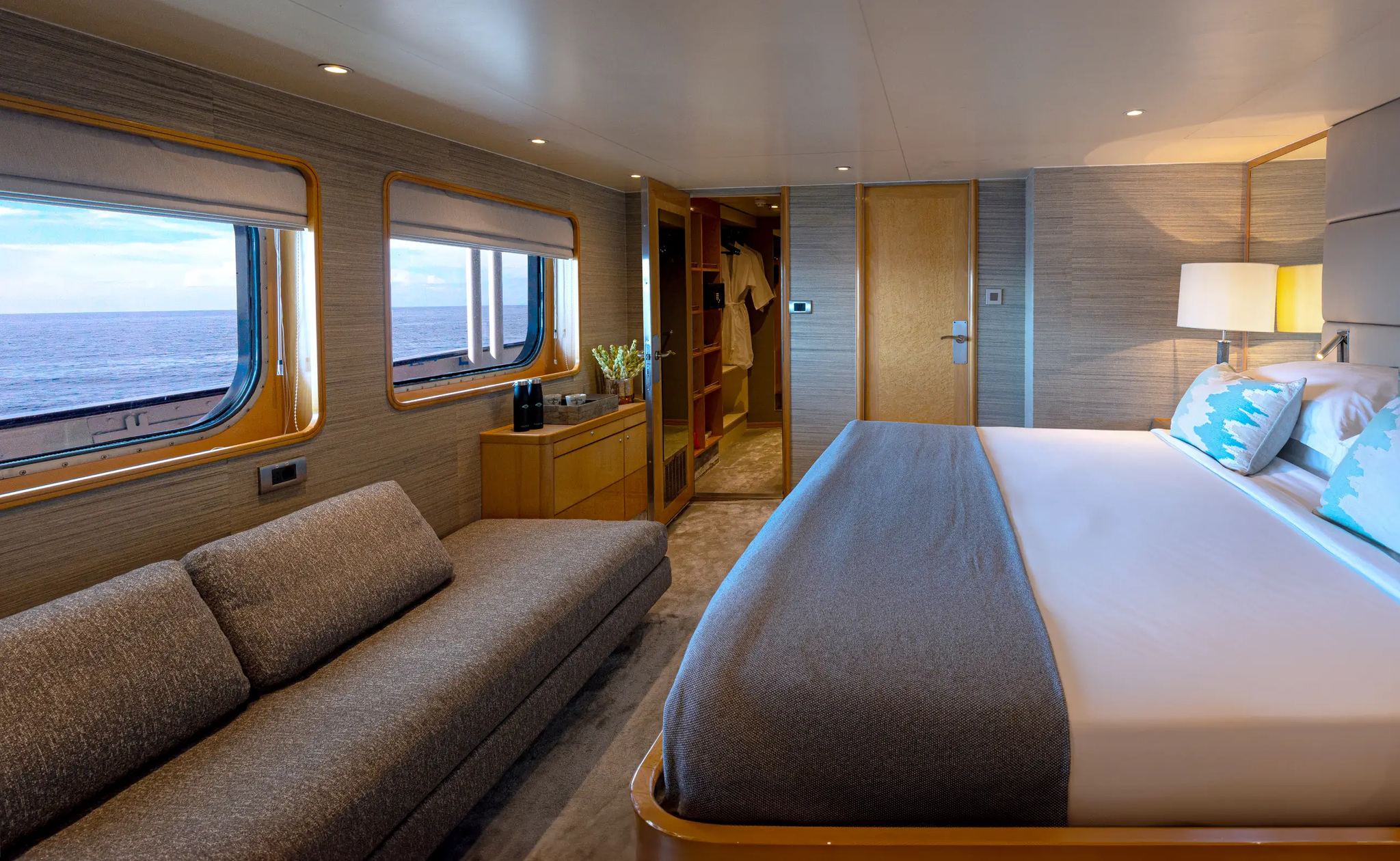 Cabin 303, Category I, with a king bed facing a long sofa below two windows