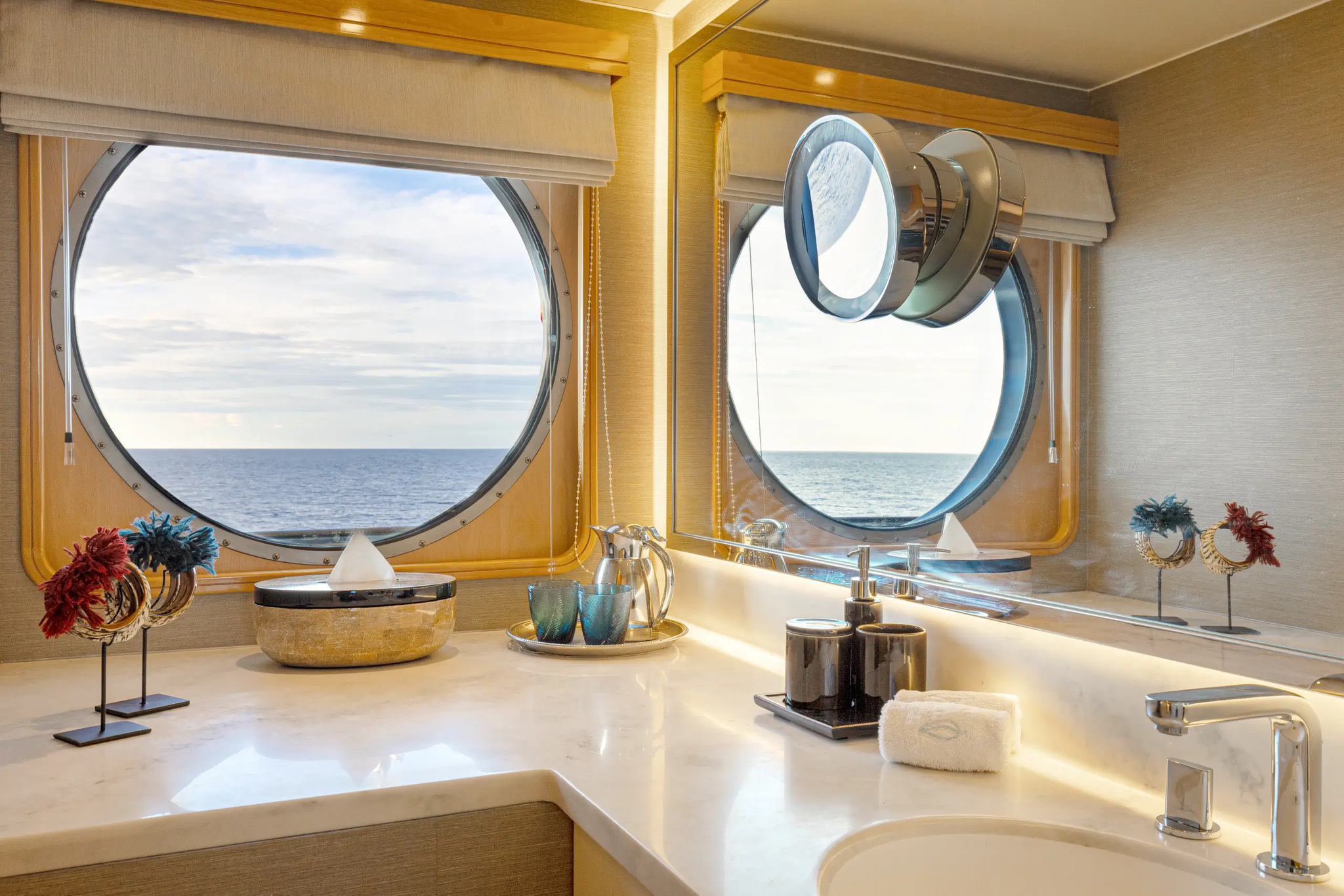 The bathroom of cabin 401, with a marble basin below two round windows onto the sea