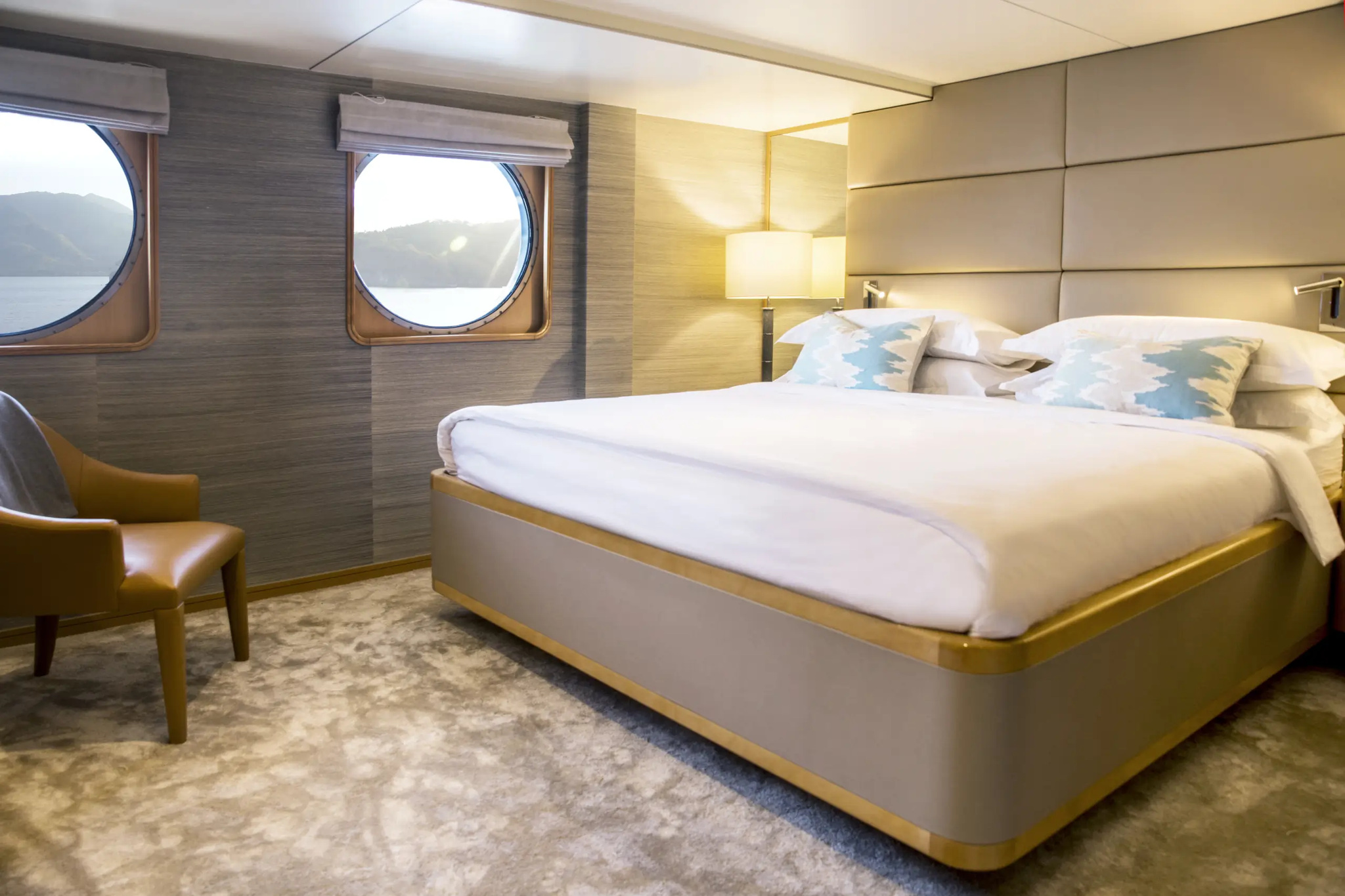 Cabin 401, Category II, with a king bed, an armchair and two large round windows